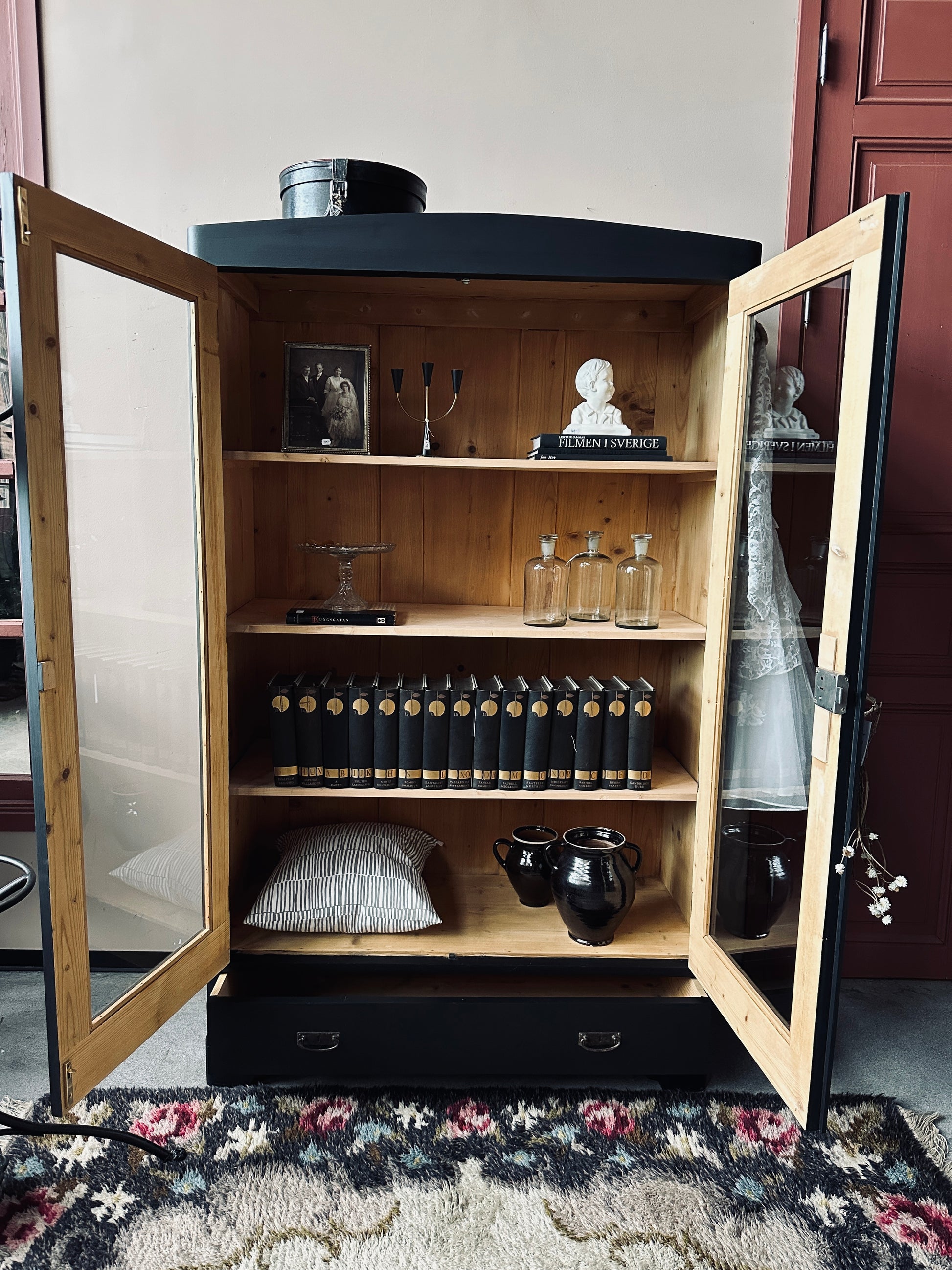 Ett gammalt, vackert vitrinskåp med rundad överkant.Skåpet har två glasdörrar.