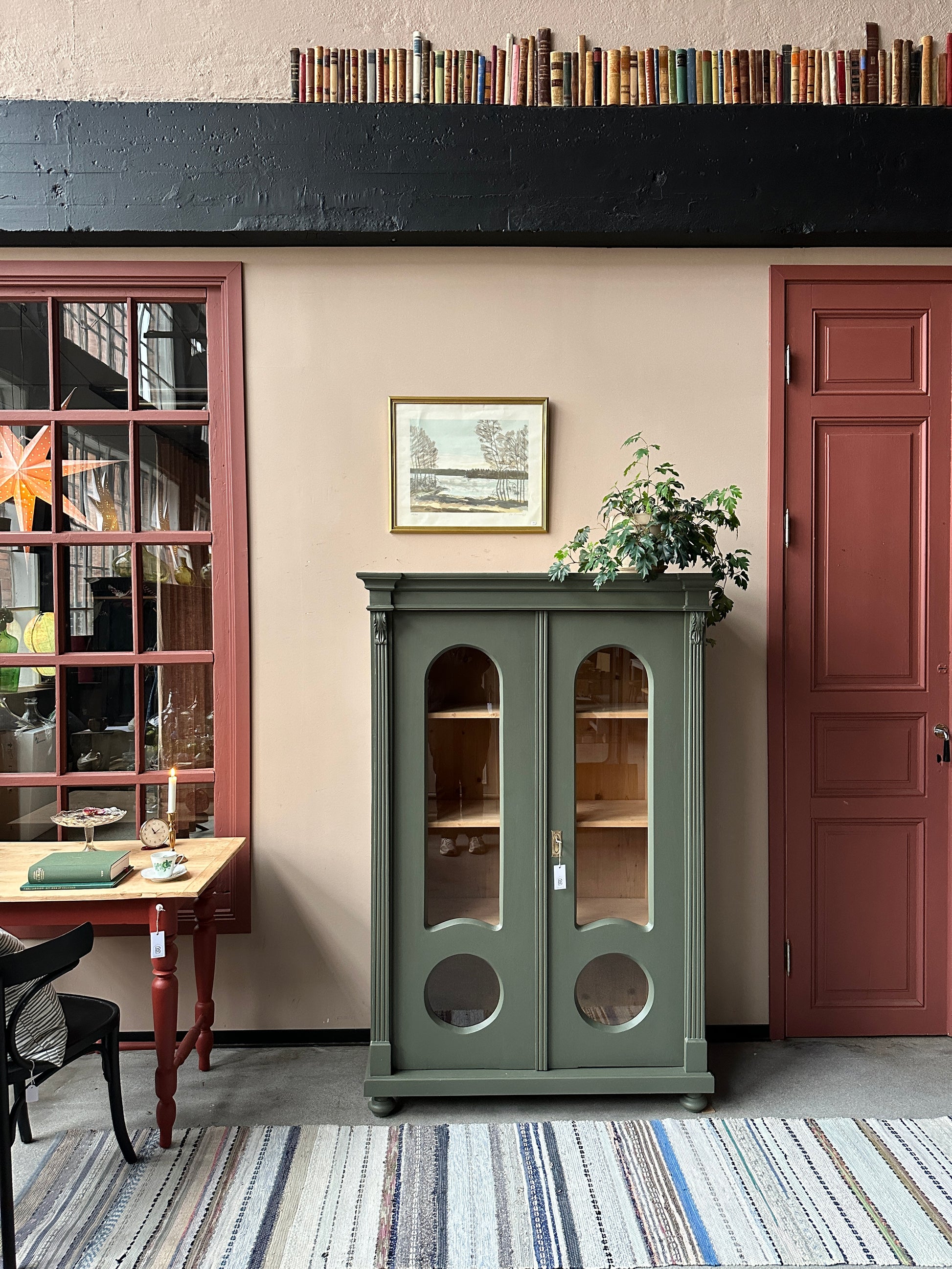 Ett gammalt, vackert vitrinskåp med fina detaljer i de rundade formerna och det arbetade krönet.