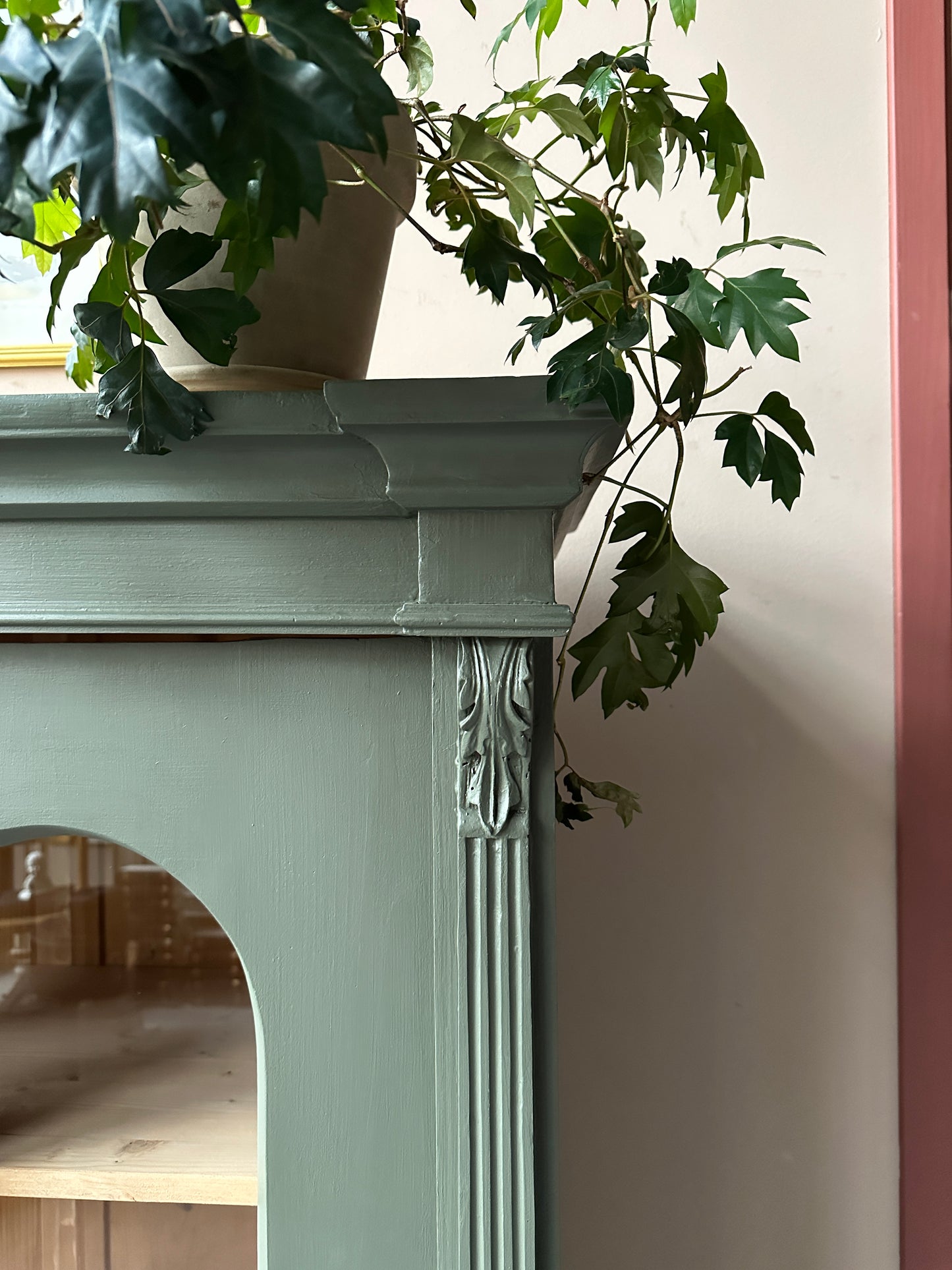 Ett gammalt, vackert vitrinskåp med fina detaljer i de rundade formerna och det arbetade krönet. Detaljbild.