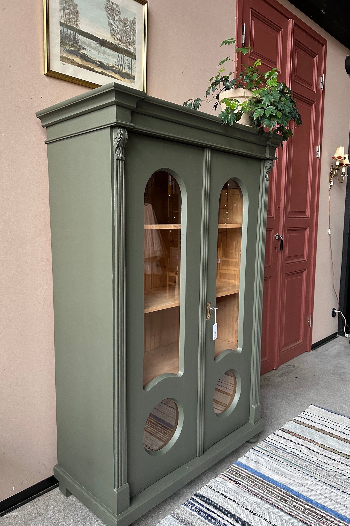 Ett gammalt, vackert vitrinskåp med fina detaljer i de rundade formerna och det arbetade krönet.