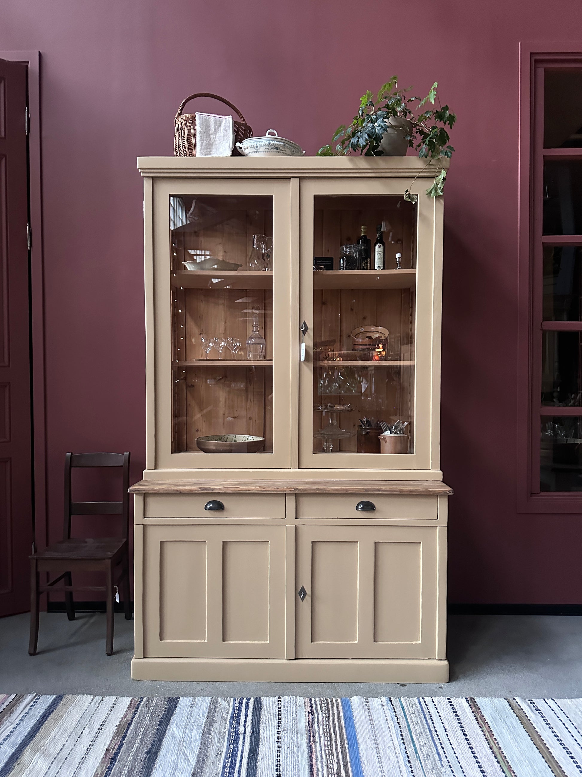 Ett gammalt, vackert köksskåp med härlig utformning och med raka och klassiska detaljer.Skåpet har mängder av praktisk förvaring tack vare såväl vitrindörrar samt skåp som diverse lådor och en svagt pigmenterad bänkskiva i en hårdvaxolja.