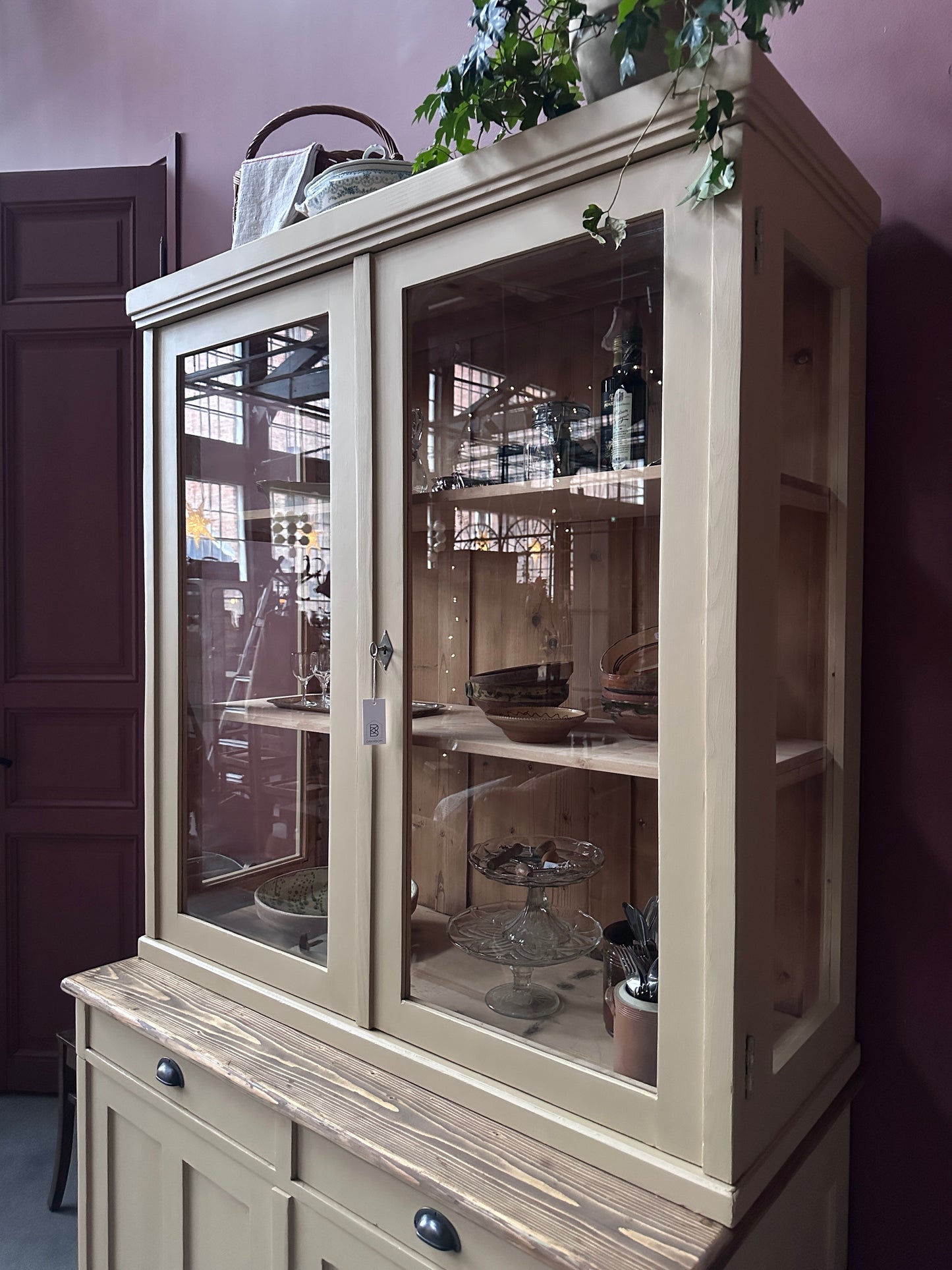 Ett gammalt, vackert köksskåp med härlig utformning och med raka och klassiska detaljer.Skåpet har mängder av praktisk förvaring tack vare såväl vitrindörrar samt skåp som diverse lådor och en svagt pigmenterad bänkskiva i en hårdvaxolja.