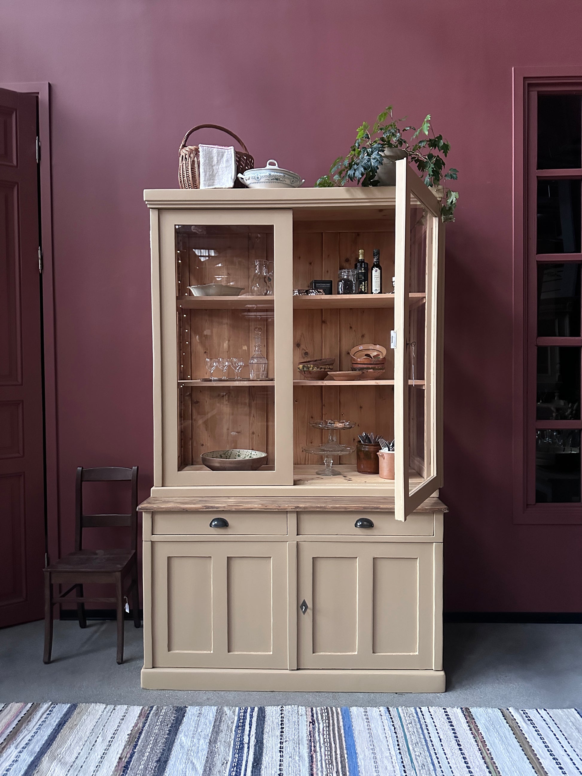 Ett gammalt, vackert köksskåp med härlig utformning och med raka och klassiska detaljer.Skåpet har mängder av praktisk förvaring tack vare såväl vitrindörrar samt skåp som diverse lådor och en svagt pigmenterad bänkskiva i en hårdvaxolja.