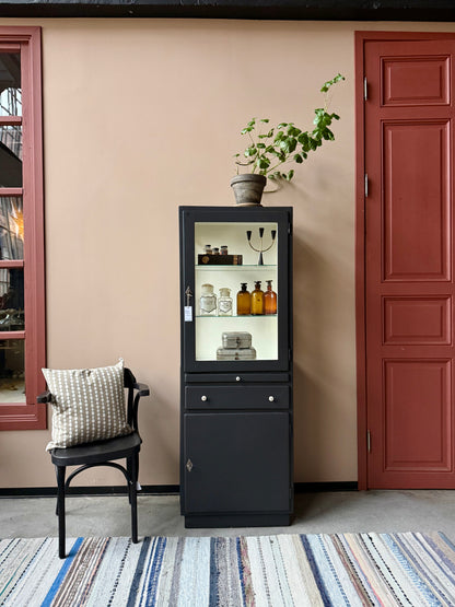 Ett gammalt läckert läkarskåp i trä med två hyllor i glas och även glas i sidan. Ett perfekt skåp för badrummet eller som vitrinskåp i köket .Skåpet har både en utdragbar skiva i trä samt låda och skåp med dold förvaring nertill och med fina porslinsknoppar. Väldigt praktiskt skåp helt enkelt. 