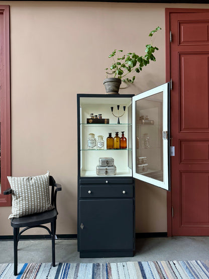 Ett gammalt läckert läkarskåp i trä med två hyllor i glas och även glas i sidan. Ett perfekt skåp för badrummet eller som vitrinskåp i köket .Skåpet har både en utdragbar skiva i trä samt låda och skåp med dold förvaring nertill och med fina porslinsknoppar. Väldigt praktiskt skåp helt enkelt. 