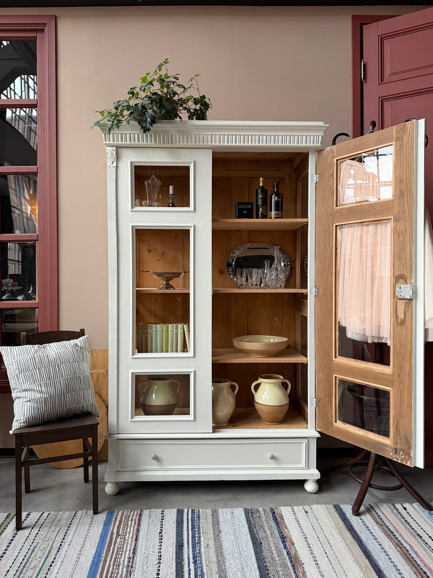 Ett gammalt vackert vitrinskåp med många fina och klassiska detaljer. Skåpet har vitringlas även i sidorna för vackert ljusinsläpp. Skåpet har i dagsläget 3 st nya och fräscha hyllplan. Skåpet har en stor och praktisk låda nertill med porslinsknoppar.