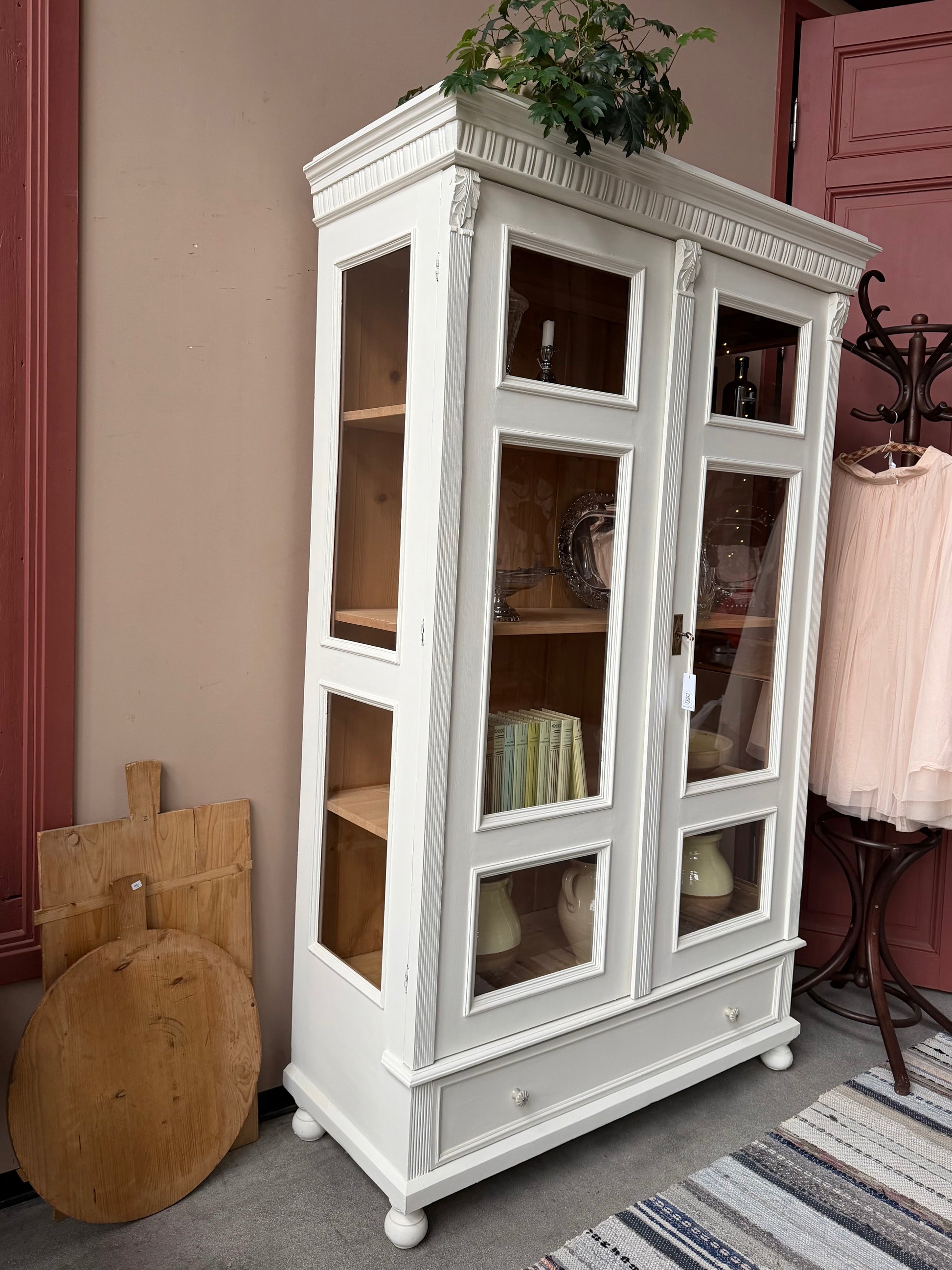 Ett gammalt vackert vitrinskåp med många fina och klassiska detaljer. Skåpet har vitringlas även i sidorna för vackert ljusinsläpp. Skåpet har i dagsläget 3 st nya och fräscha hyllplan. Skåpet har en stor och praktisk låda nertill med porslinsknoppar.