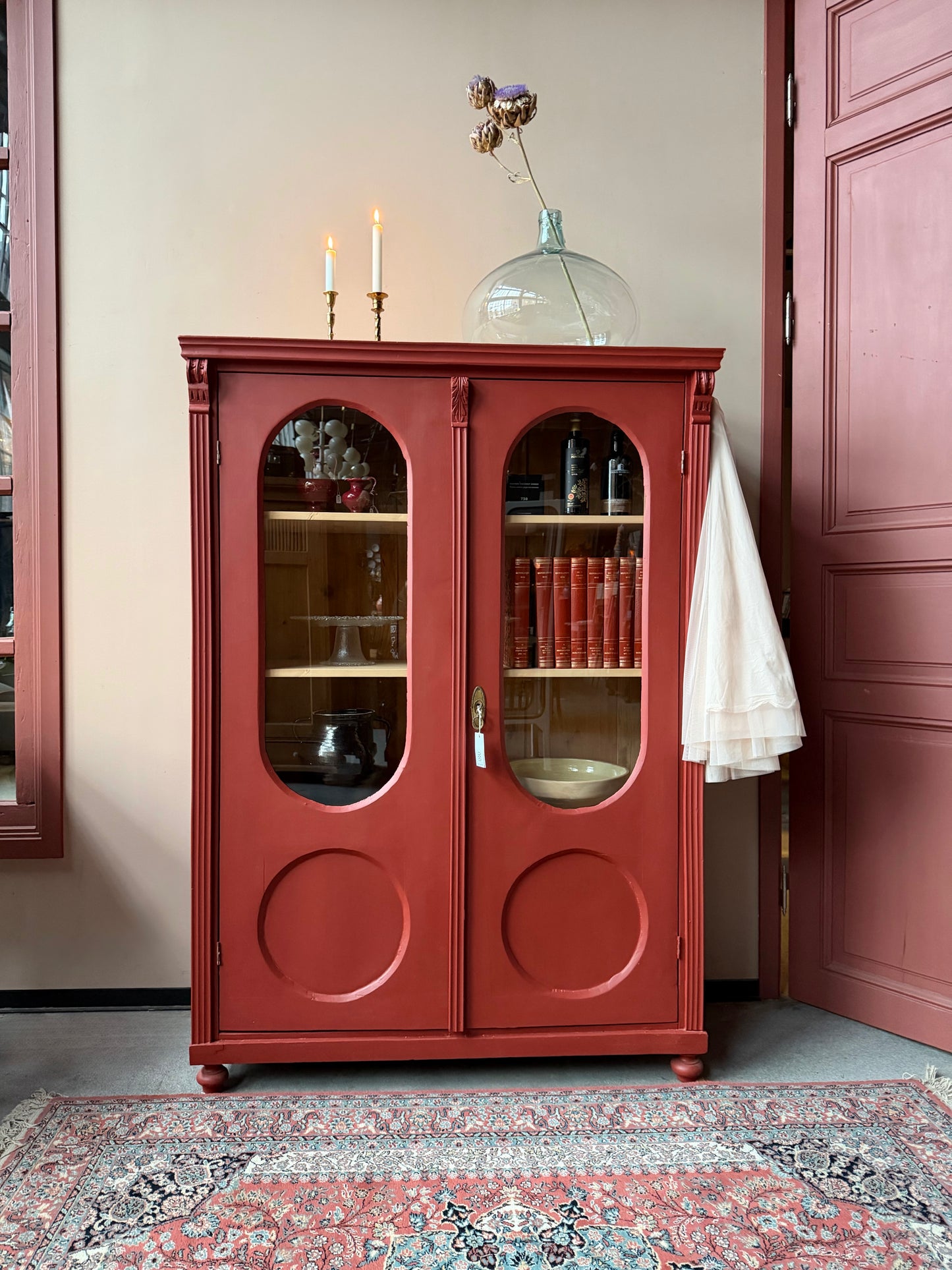 Ett gammalt vackert vitrinskåp med många fina och klassiska detaljer. Skåpet har rundade vitringlas i dörrarna vilket är en fantastiskt fin och unik utsmyckning. 