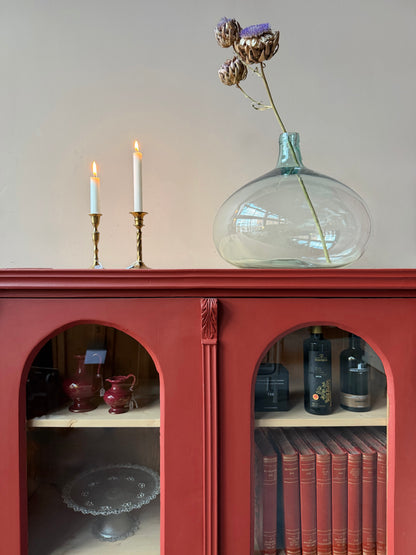 Ett gammalt vackert vitrinskåp med många fina och klassiska detaljer. Skåpet har rundade vitringlas i dörrarna vilket är en fantastiskt fin och unik utsmyckning. 