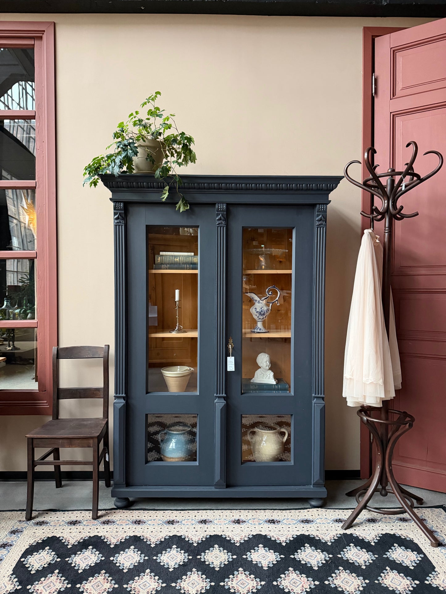 Ett gammalt vackert vitrinskåp med många vackra detaljer. Skåpet har glas hela vägen ner i dörrarna, spår i sidorna, dekorationer i hörnen samt ett vackert utsmyckat ornament uppe på krönet som går att ta bort om man föredrar det.