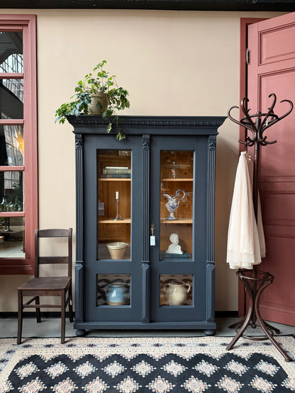 Ett gammalt vackert vitrinskåp med många vackra detaljer. Skåpet har glas hela vägen ner i dörrarna, spår i sidorna, dekorationer i hörnen samt ett vackert utsmyckat ornament uppe på krönet som går att ta bort om man föredrar det.