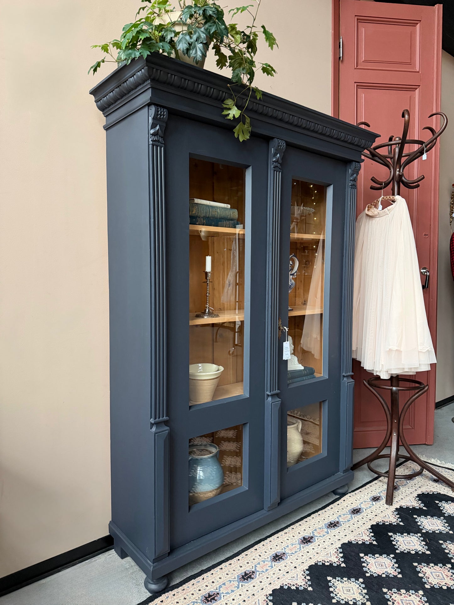 Ett gammalt vackert vitrinskåp med många vackra detaljer. Skåpet har glas hela vägen ner i dörrarna, spår i sidorna, dekorationer i hörnen samt ett vackert utsmyckat ornament uppe på krönet som går att ta bort om man föredrar det.