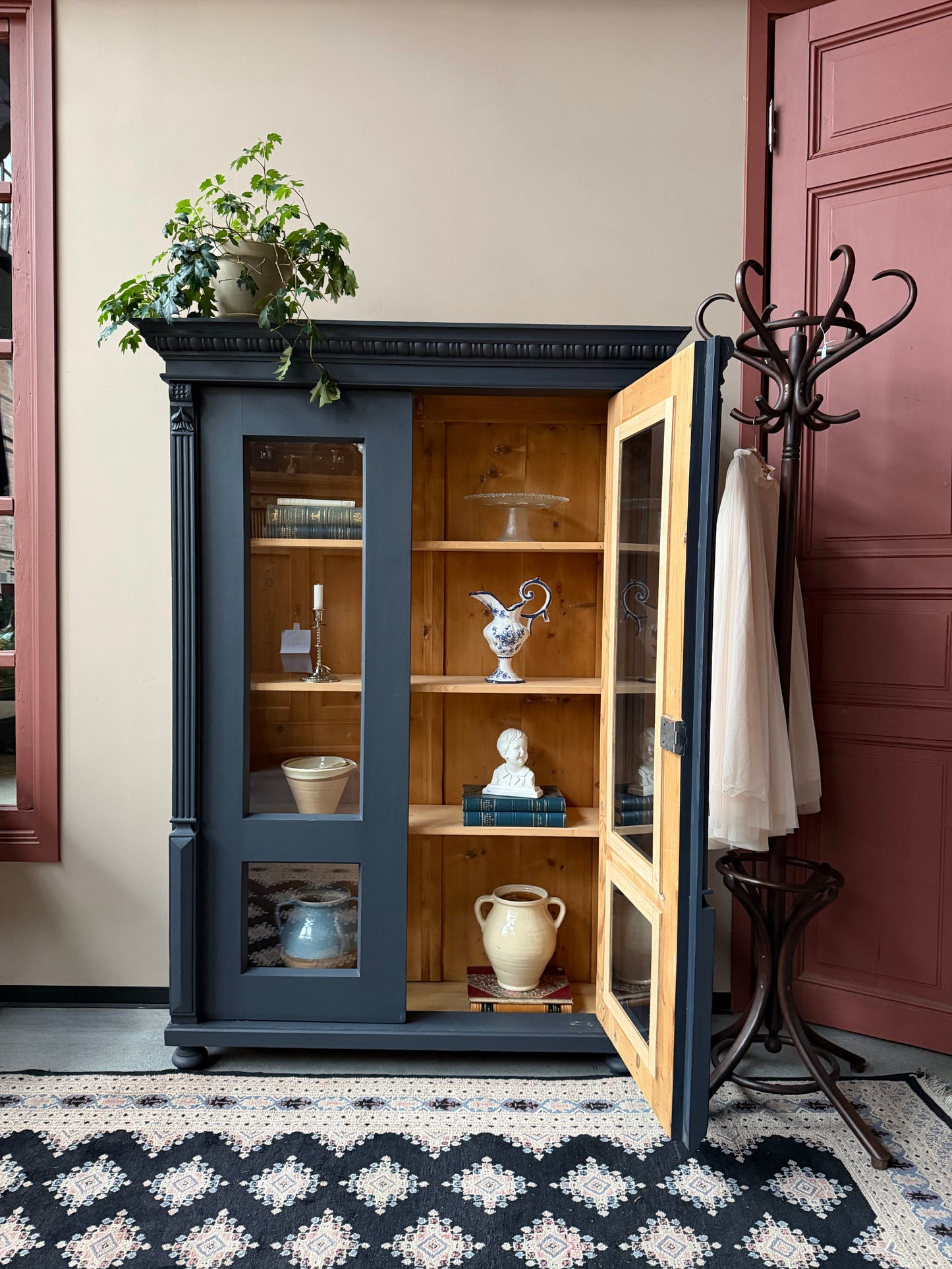 Ett gammalt vackert vitrinskåp med många vackra detaljer. Skåpet har glas hela vägen ner i dörrarna, spår i sidorna, dekorationer i hörnen samt ett vackert utsmyckat ornament uppe på krönet som går att ta bort om man föredrar det.