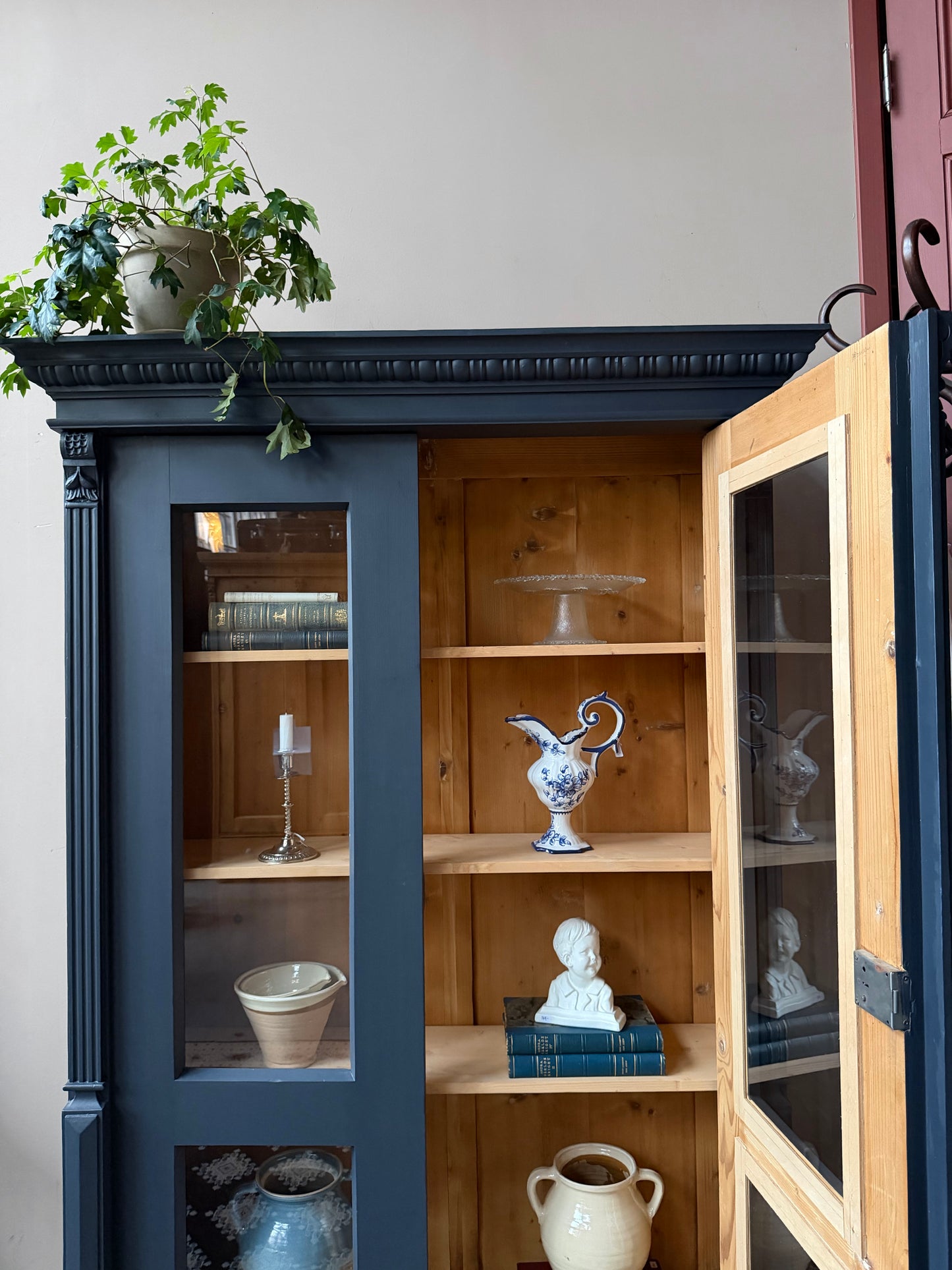 Ett gammalt vackert vitrinskåp med många vackra detaljer. Skåpet har glas hela vägen ner i dörrarna, spår i sidorna, dekorationer i hörnen samt ett vackert utsmyckat ornament uppe på krönet som går att ta bort om man föredrar det.