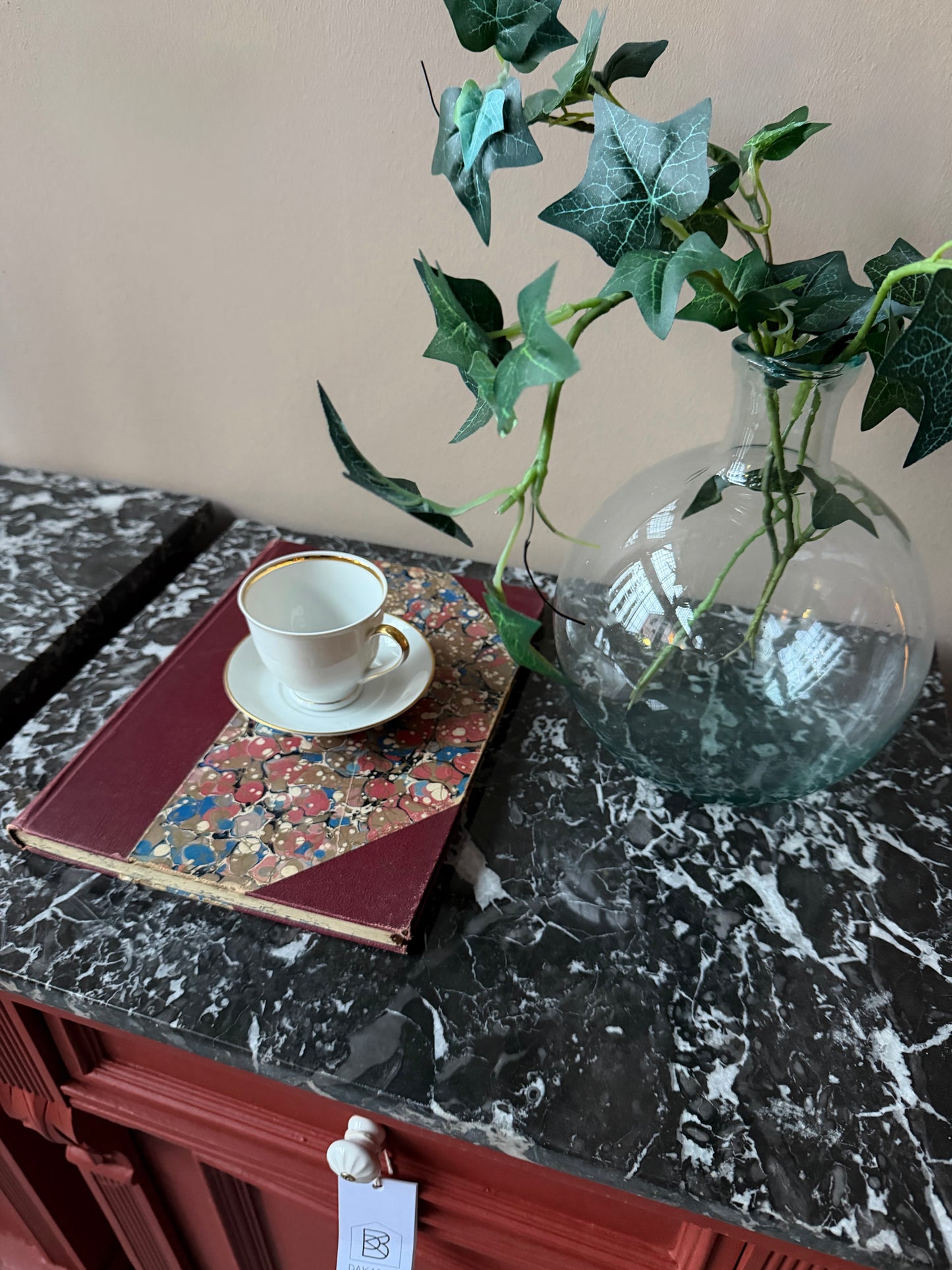 Ett par gamla, vackra sängbord med fin utsmyckning och klassisk form med både låda och skåp. Sängborden har en fantastiskt vacker svart/vit marmorerad toppskiva i sten som är avtagbar. Sängborden är varsamt renoverade och slutligen penselmålade med en matt snickerifärg i Dakaboms varmröda kulör.