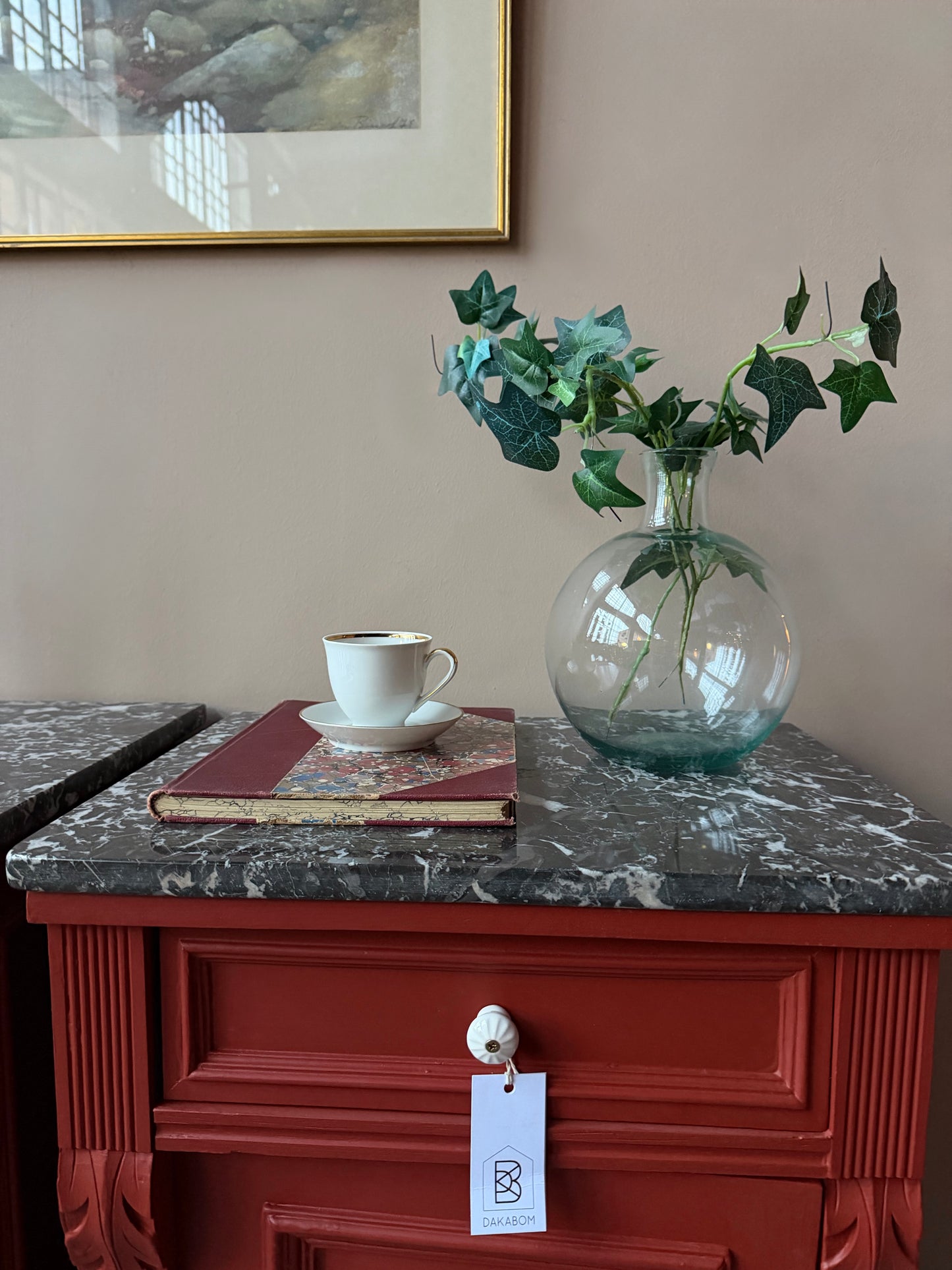 Ett par gamla, vackra sängbord med fin utsmyckning och klassisk form med både låda och skåp. Sängborden har en fantastiskt vacker svart/vit marmorerad toppskiva i sten som är avtagbar. Sängborden är varsamt renoverade och slutligen penselmålade med en matt snickerifärg i Dakaboms varmröda kulör.