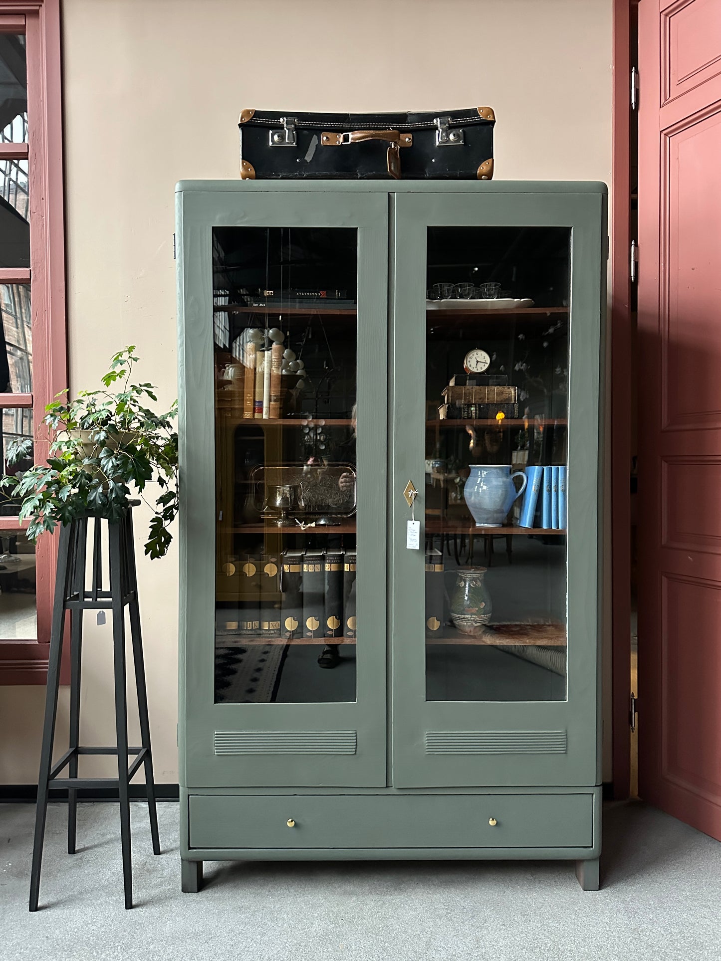 Ett gammalt vackert vitrinskåp men raka och mjuka former och enkla detaljer. Skåpet har en bred praktiskt låda nertill med nya knoppar i äldre stil.