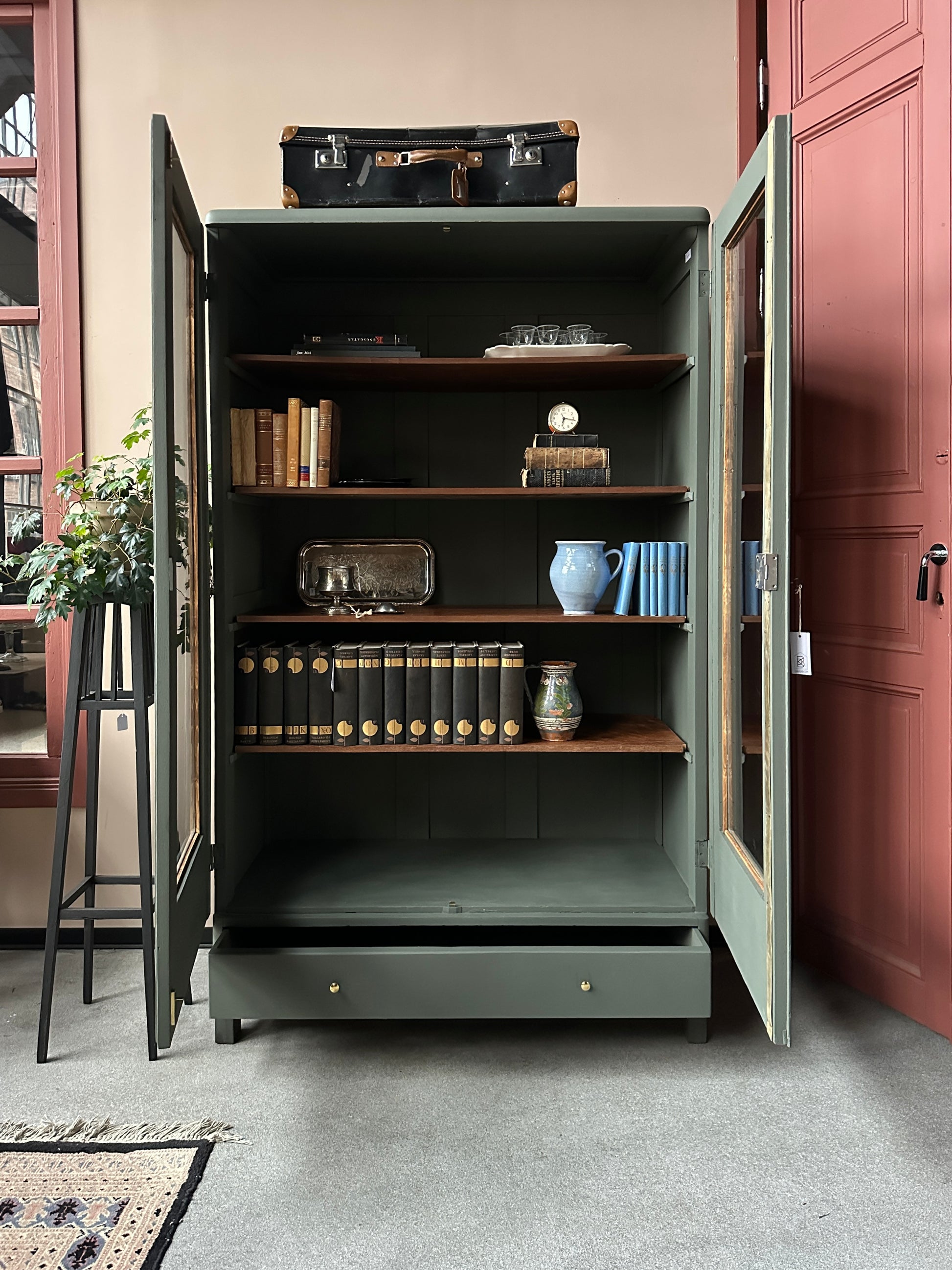 Ett gammalt vackert vitrinskåp men raka och mjuka former och enkla detaljer. Skåpet har en bred praktiskt låda nertill med nya knoppar i äldre stil.