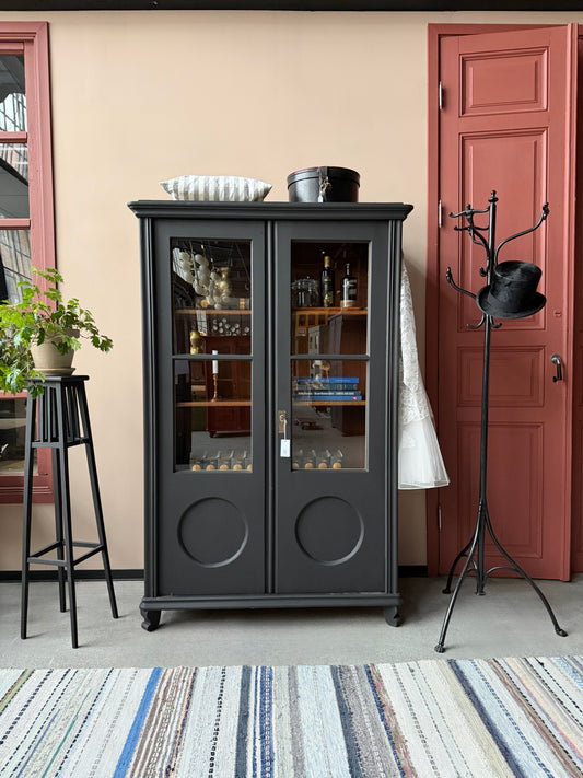 Ett gammalt, vackert vitrinskåp med fina detaljer i de raka vitrinfönsterna med spröjs och de rundade formerna i speglarna. 