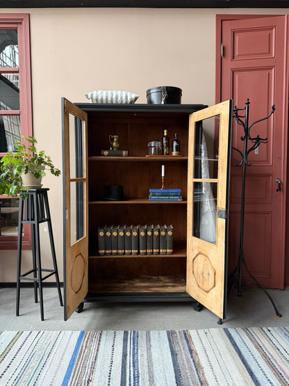 Ett gammalt, vackert vitrinskåp med fina detaljer i de raka vitrinfönsterna med spröjs och de rundade formerna i speglarna. 