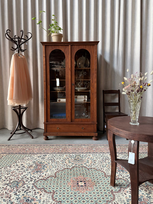 Ett gammalt, elegant vitrinskåp med runda former.