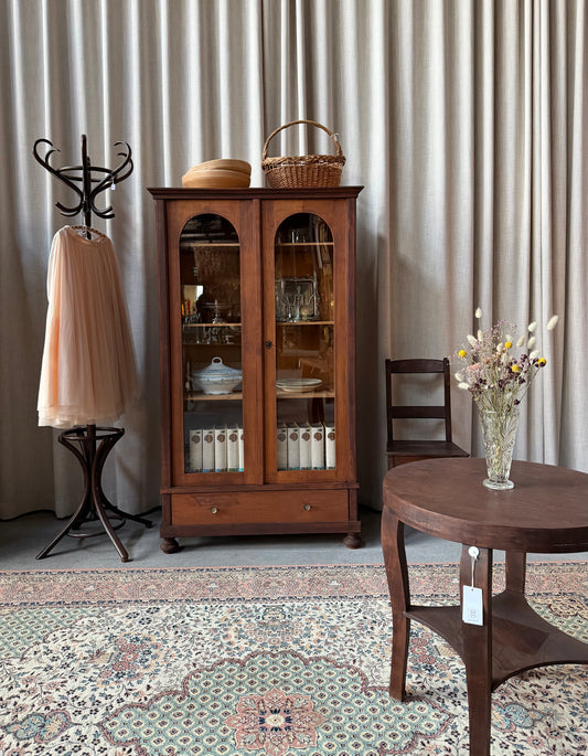 Ett gammalt, elegant vitrinskåp med runda former. 