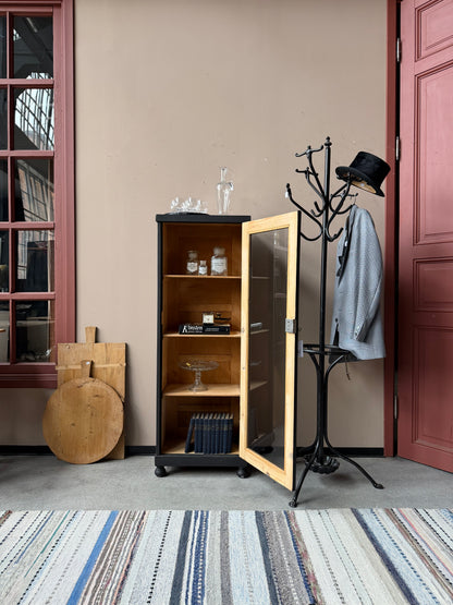 Ett gammalt vackert svart 1-dörrars vitrinskåp med glas i dörren. Skåpet har ett klassiskt uttryck.