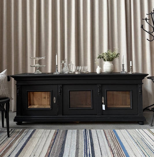 Ett vackert sidebord med fin utsmyckning och med vitrin i sidan.