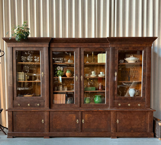 Ett gammalt vackert och ståtligt vitrinskåp i valnöt med dess raka linjer och  med utsmyckade detaljer i beslagen.