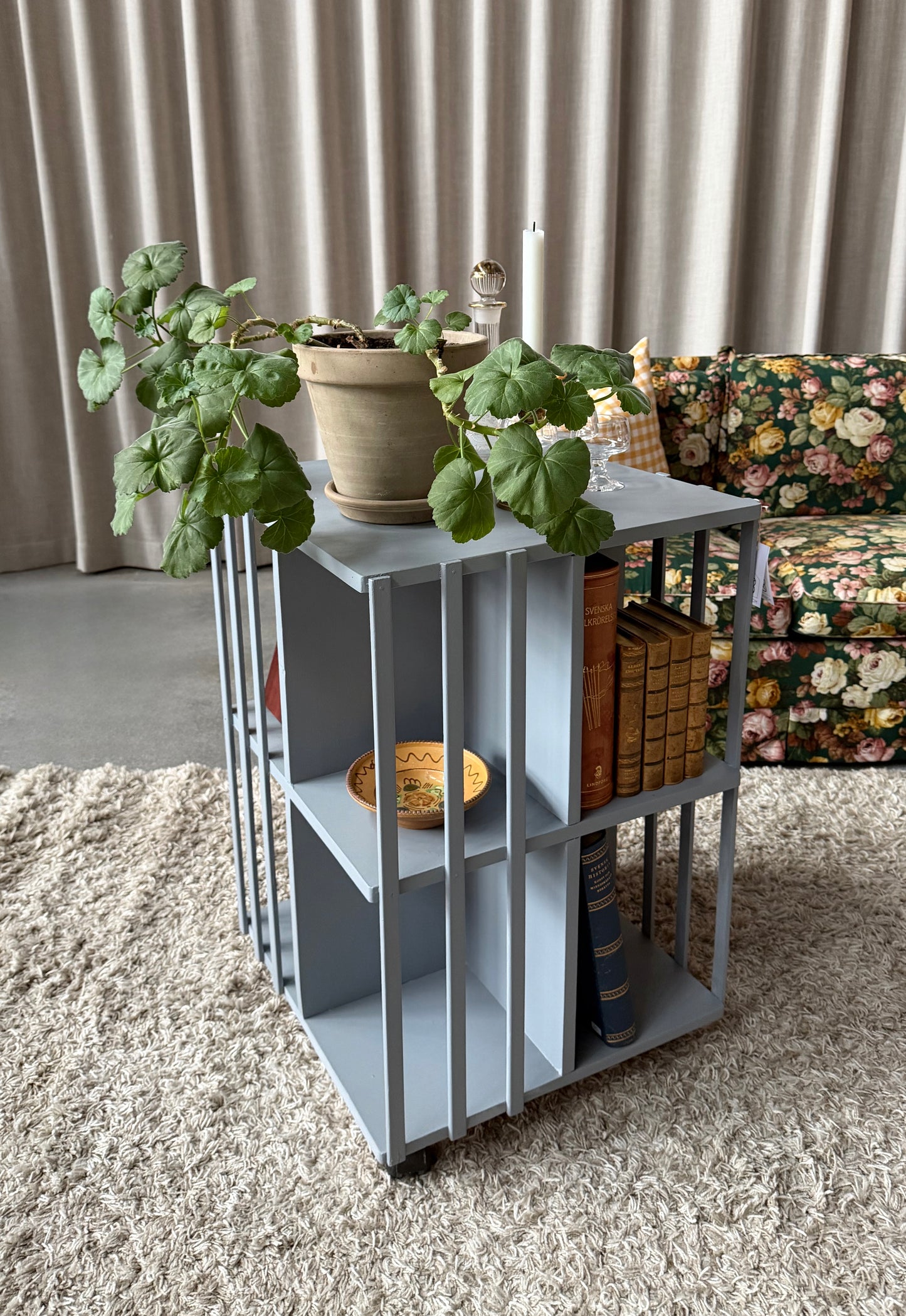 Ett vackert kvadratiskt sidebord/litet bord på hjul med ljuvliga små hyllor/fack på alla sidor vilket gör att det passar fint i rummet som sidebord att fylla med böcker och andra stilleben. Det är varsamt renoverat och målat i en ljust blå/grå kulör. 