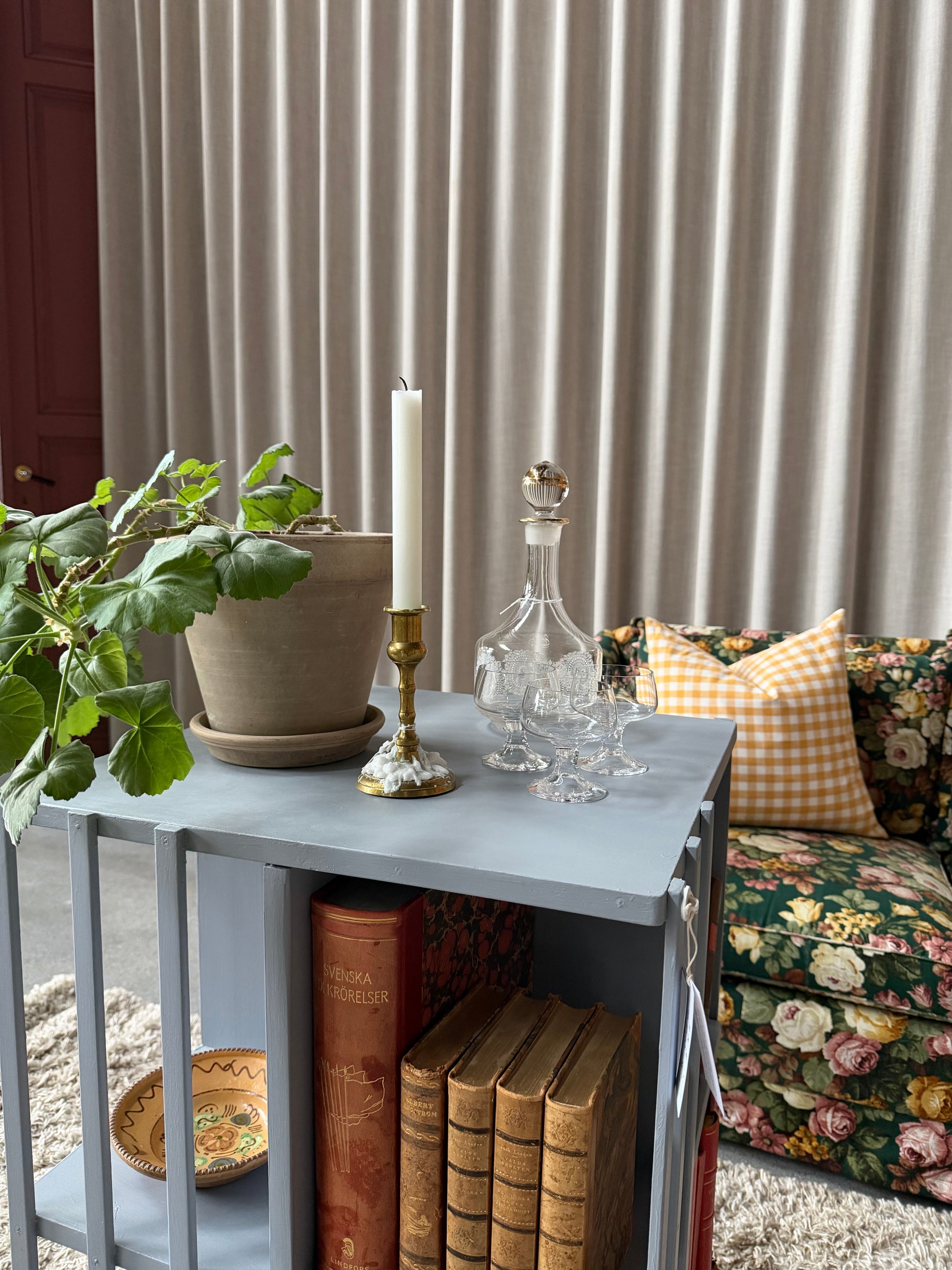 Ett vackert kvadratiskt sidebord/litet bord på hjul med ljuvliga små hyllor/fack på alla sidor vilket gör att det passar fint i rummet som sidebord att fylla med böcker och andra stilleben. Det är varsamt renoverat och målat i en ljust blå/grå kulör. 