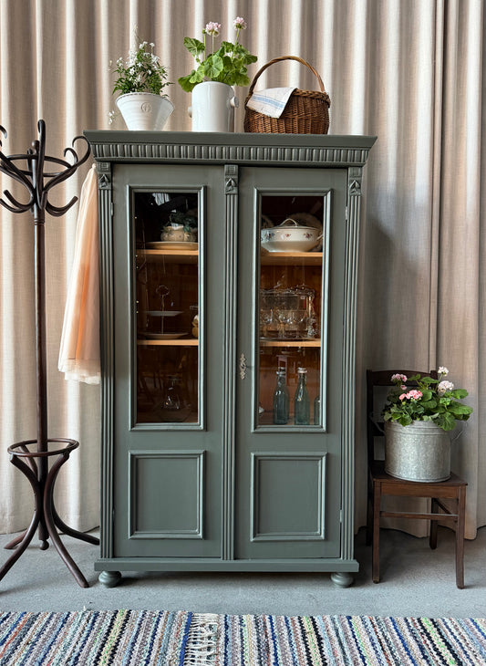 Ett vackert gammalt vitrinskåp med klassiska former och fina detaljer. Då skåpet har både vitringlas och dold förvaring blir denna möbel både vacker och praktisk.