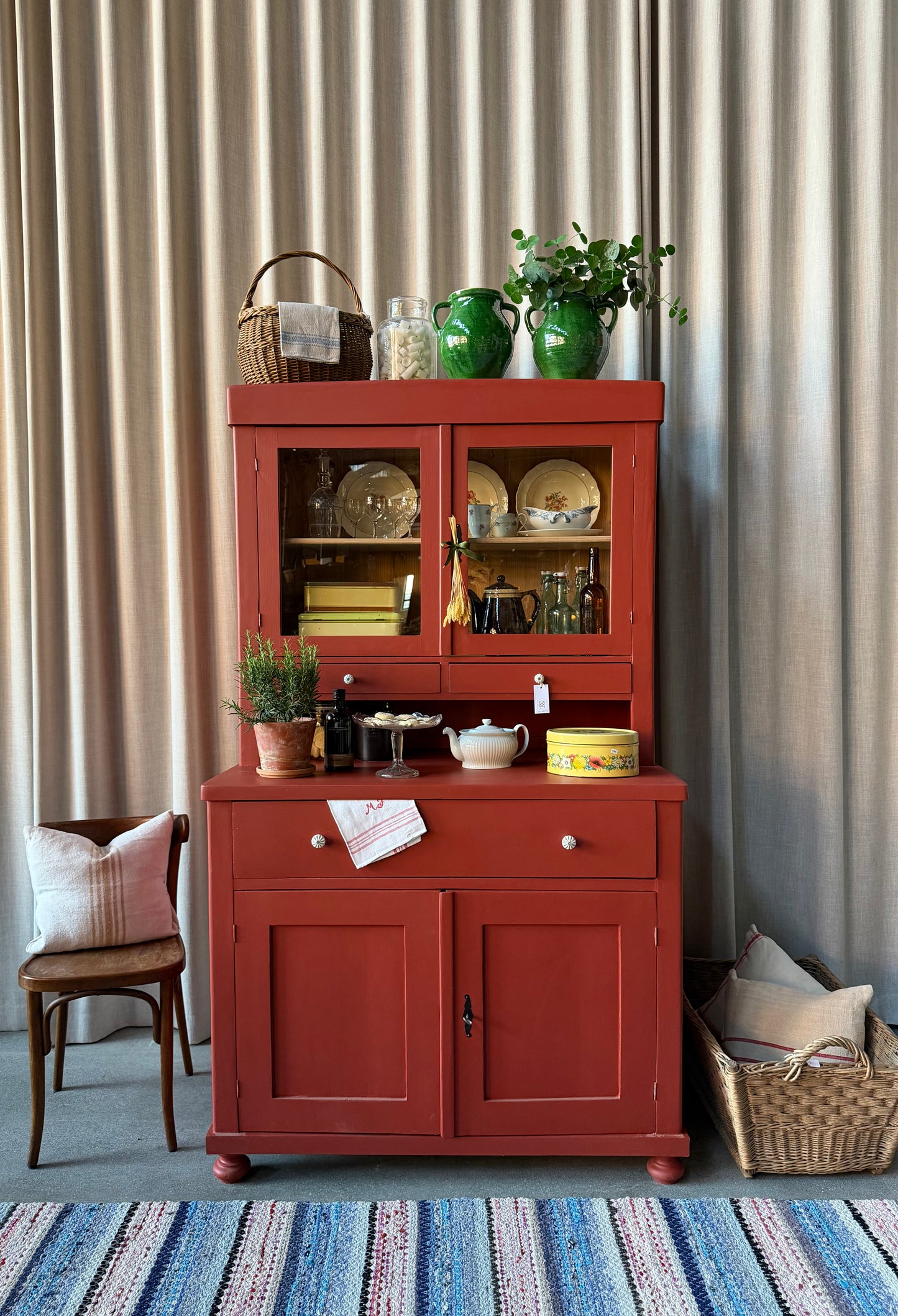 Ett gammalt, vackert och charmigt köksskåp i varmröd kulör med härlig utformning.
