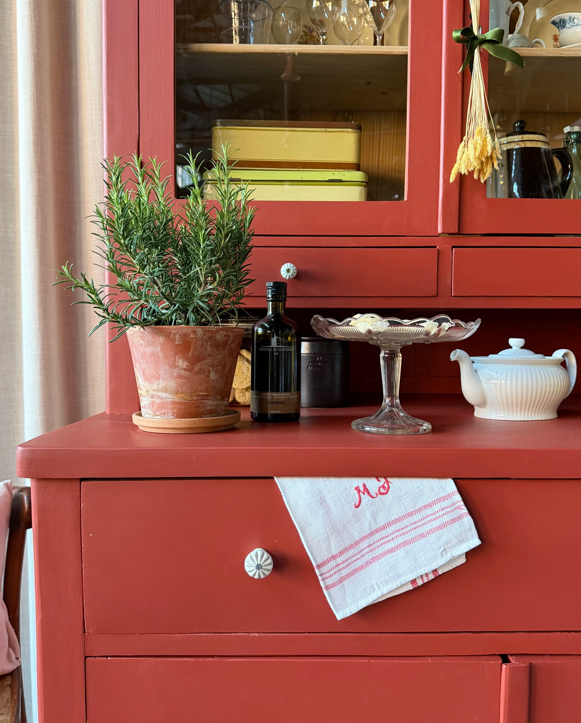 Ett gammalt, vackert och charmigt köksskåp i varmröd kulör med härlig utformning.