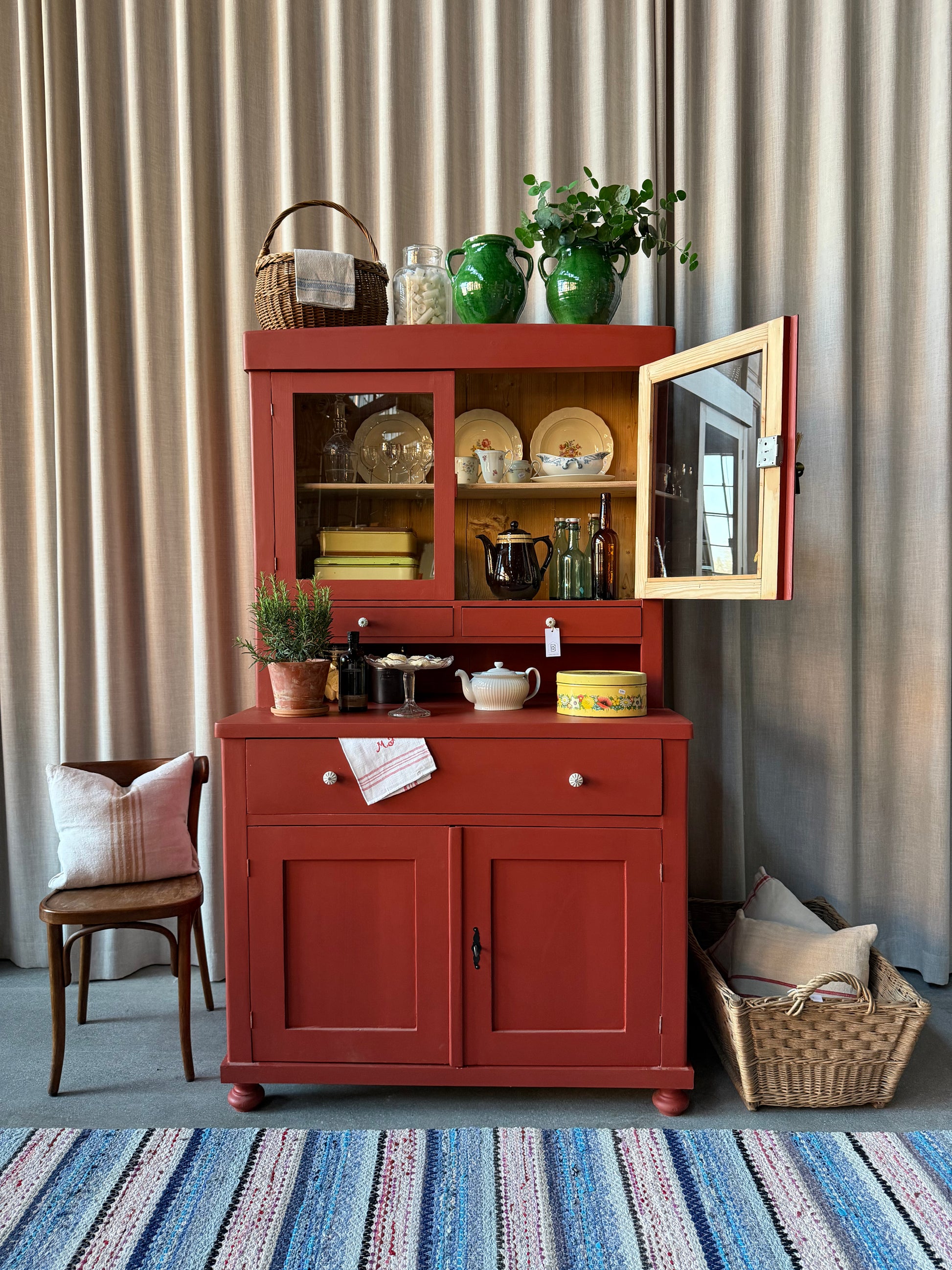 Ett gammalt, vackert och charmigt köksskåp i varmröd kulör med härlig utformning.