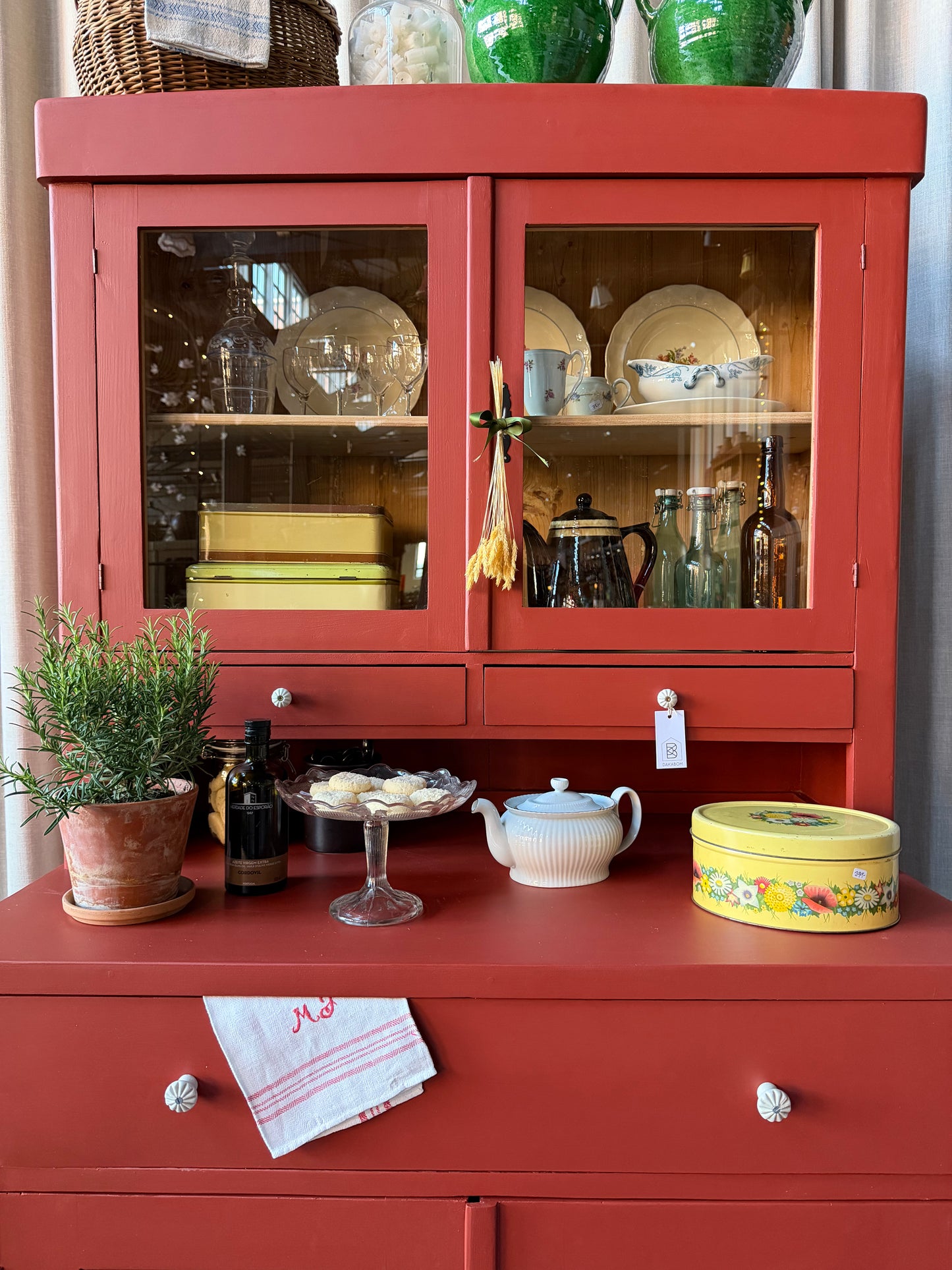 Ett gammalt, vackert och charmigt köksskåp i varmröd kulör med härlig utformning.
