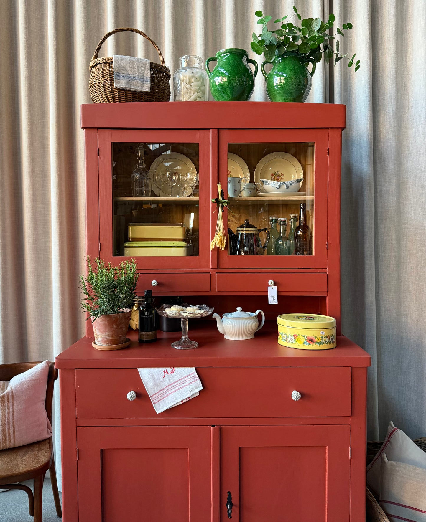 Ett gammalt, vackert och charmigt köksskåp i varmröd kulör med härlig utformning.