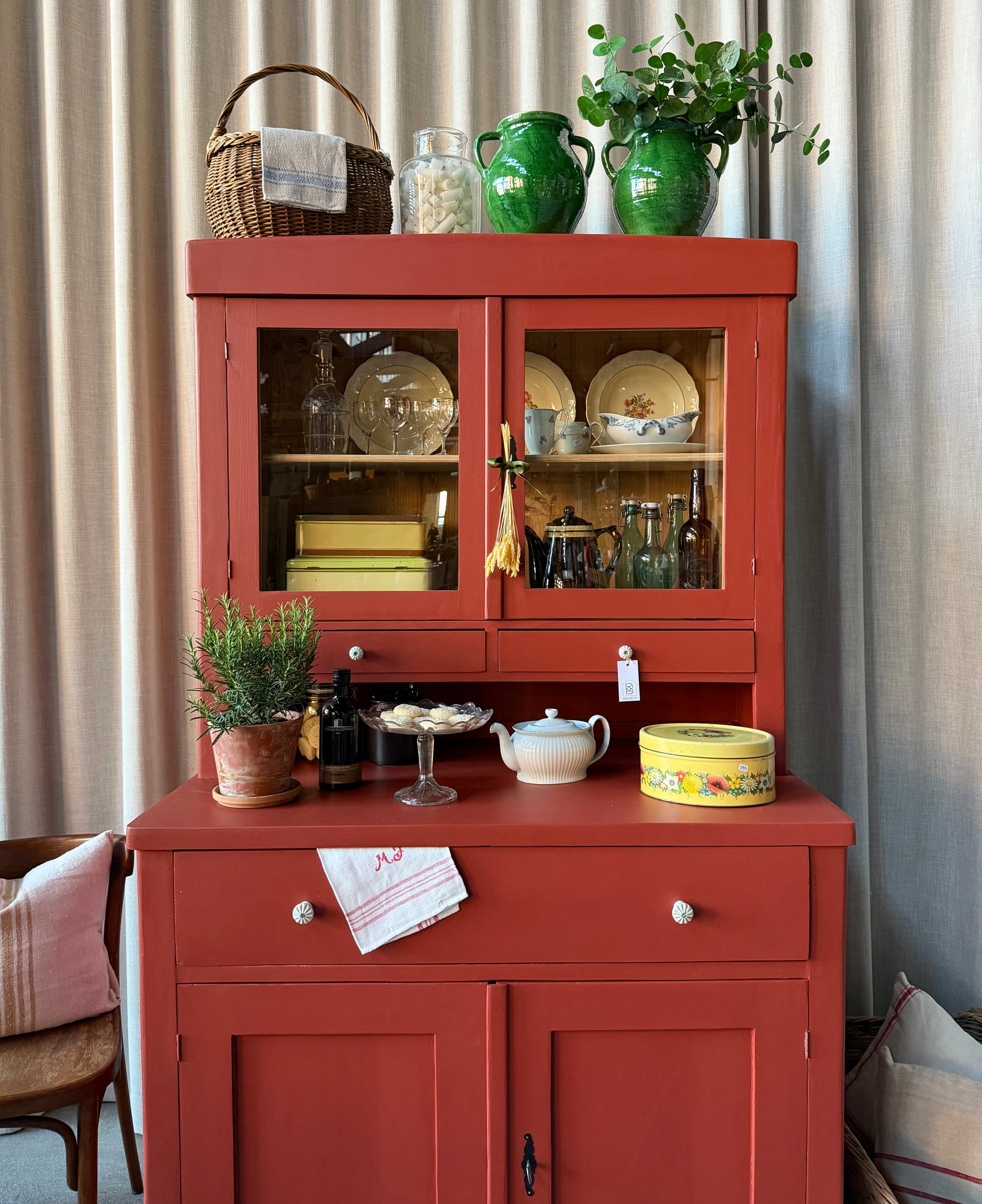 Ett gammalt, vackert och charmigt köksskåp i varmröd kulör med härlig utformning.