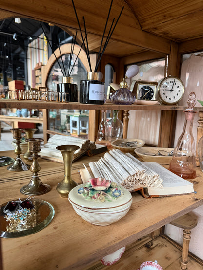 Ett gammalt, elegant vitrinskåp/displayskåp med ett stort glas samt glas i sidan för vackert ljusinsläpp. På skåpets insida sitter en spegel. 