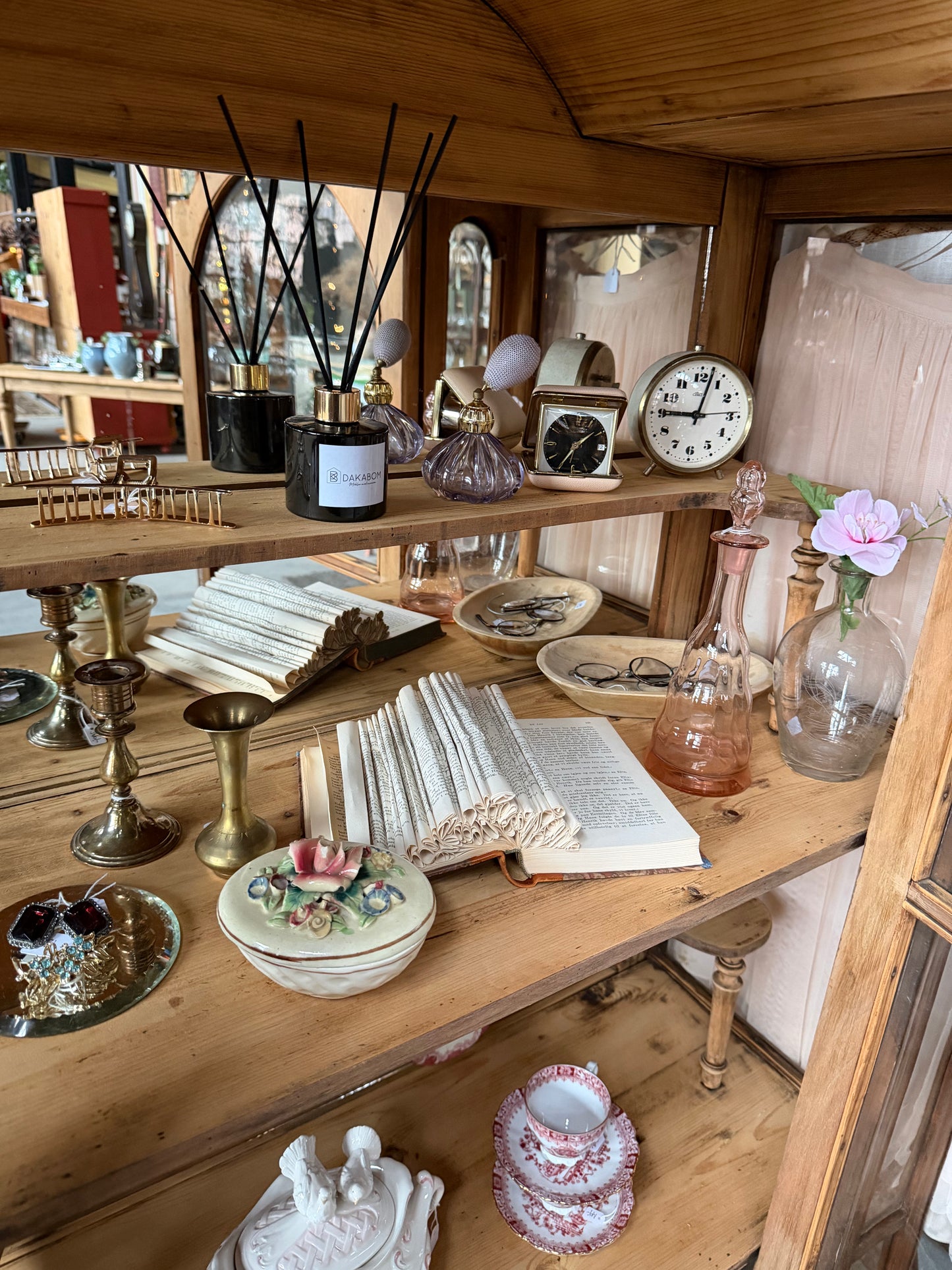 Ett gammalt, elegant vitrinskåp/displayskåp med ett stort glas samt glas i sidan för vackert ljusinsläpp. På skåpets insida sitter en spegel. 