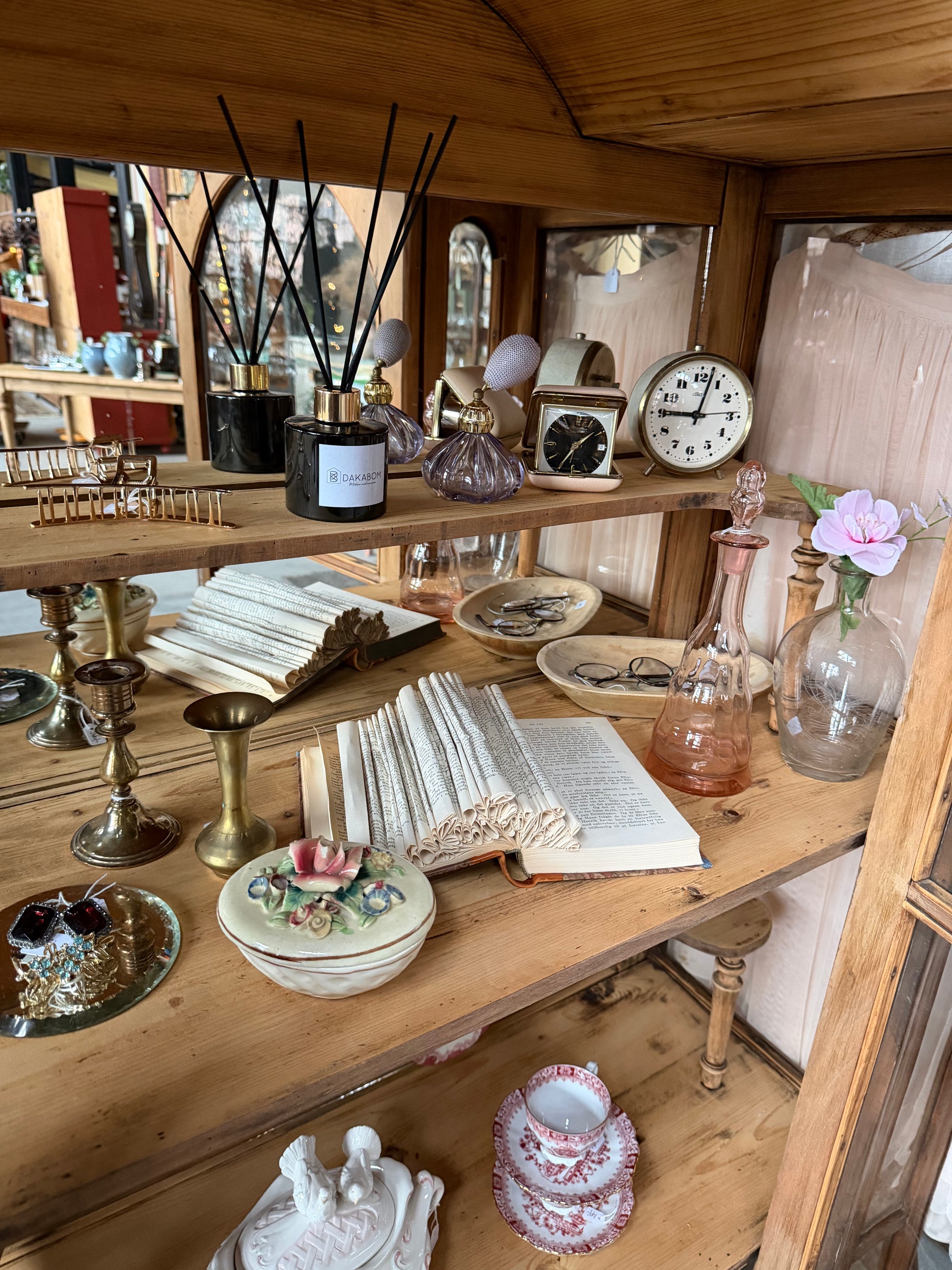 Ett gammalt, elegant vitrinskåp/displayskåp med ett stort glas samt glas i sidan för vackert ljusinsläpp. På skåpets insida sitter en spegel. 