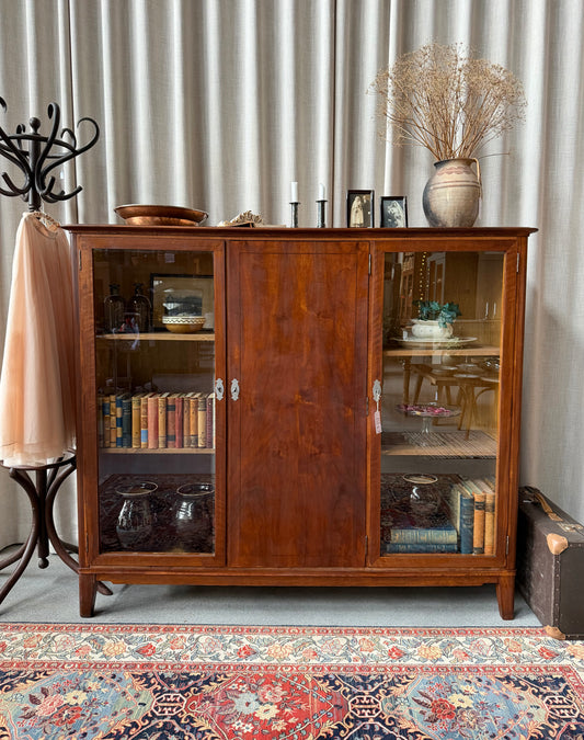 En gammal, elegant skänk med både vitrin och en täckt skåpdörr i mitten. 