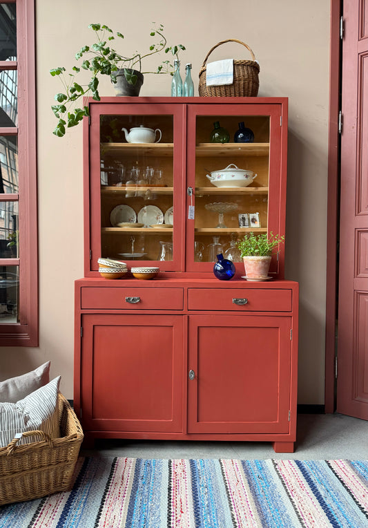 Ett gammalt, vackert och charmigt köksskåp i varmröd kulör med härlig utformning.
