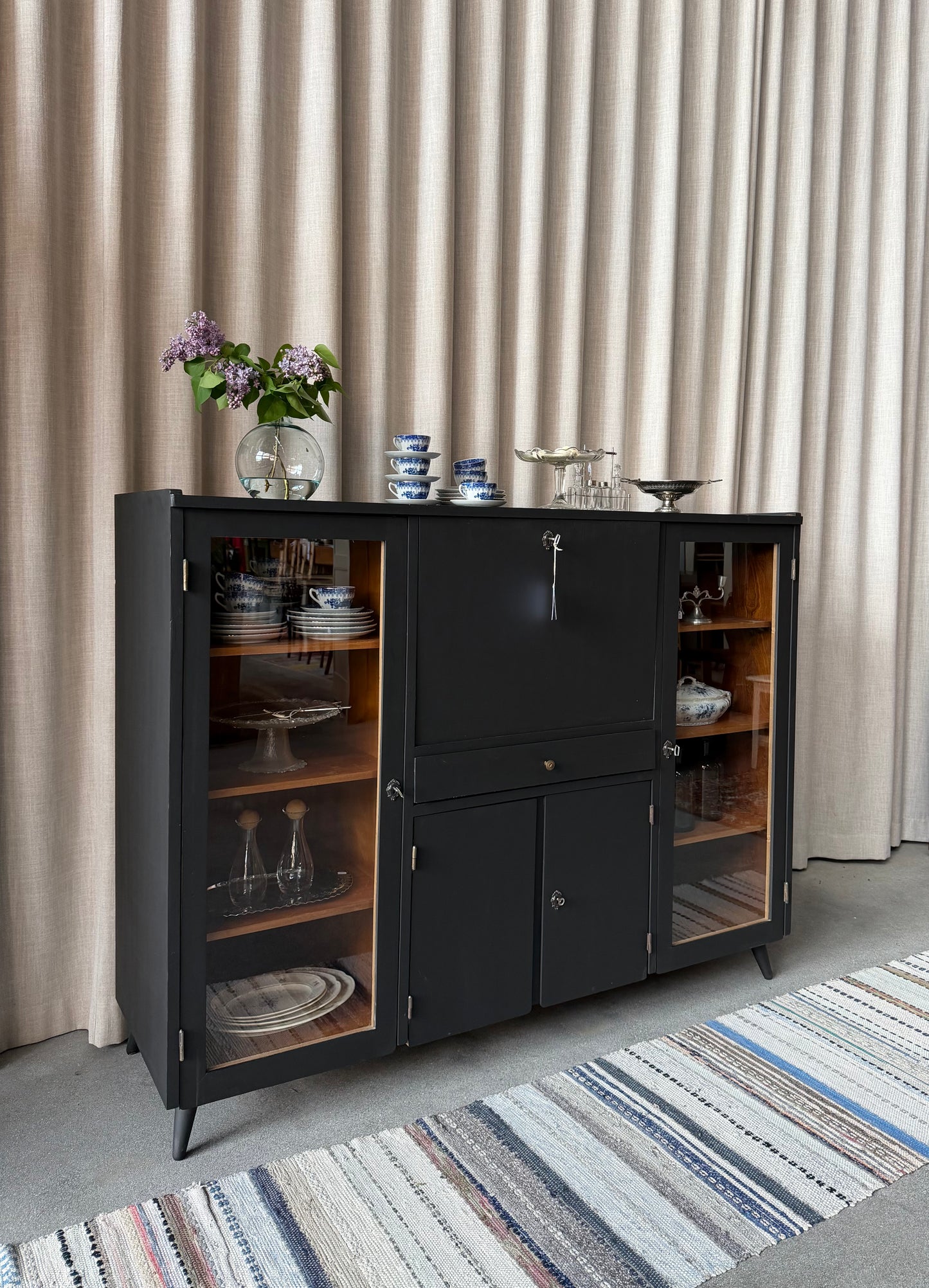 En gammal, elegant möbel som kan användas som skänk/sekretär/vitrinskåp. Perfekt för dig som önskar en både praktisk, elegant och otroligt charmig möbel där du kan "gömma undan" datorn i sekretären när du arbetat klart. Skåpet har i dagsläget flera hyllplan i vitrindelen samt en hylla i det täckta skåpet nedtill. Det finns även en liten låda. 