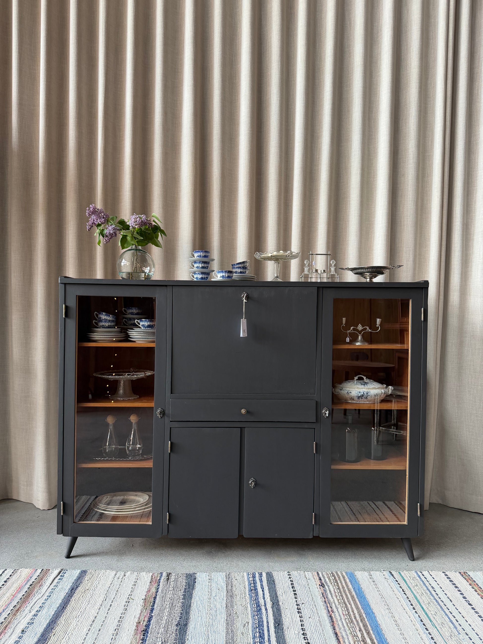 En gammal, elegant möbel som kan användas som skänk/sekretär/vitrinskåp. Perfekt för dig som önskar en både praktisk, elegant och otroligt charmig möbel där du kan "gömma undan" datorn i sekretären när du arbetat klart. Skåpet har i dagsläget flera hyllplan i vitrindelen samt en hylla i det täckta skåpet nedtill. Det finns även en liten låda. 