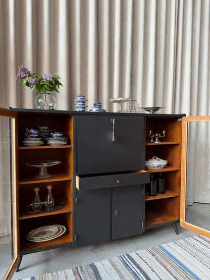 En gammal, elegant möbel som kan användas som skänk/sekretär/vitrinskåp. Perfekt för dig som önskar en både praktisk, elegant och otroligt charmig möbel där du kan "gömma undan" datorn i sekretären när du arbetat klart. Skåpet har i dagsläget flera hyllplan i vitrindelen samt en hylla i det täckta skåpet nedtill. Det finns även en liten låda. 