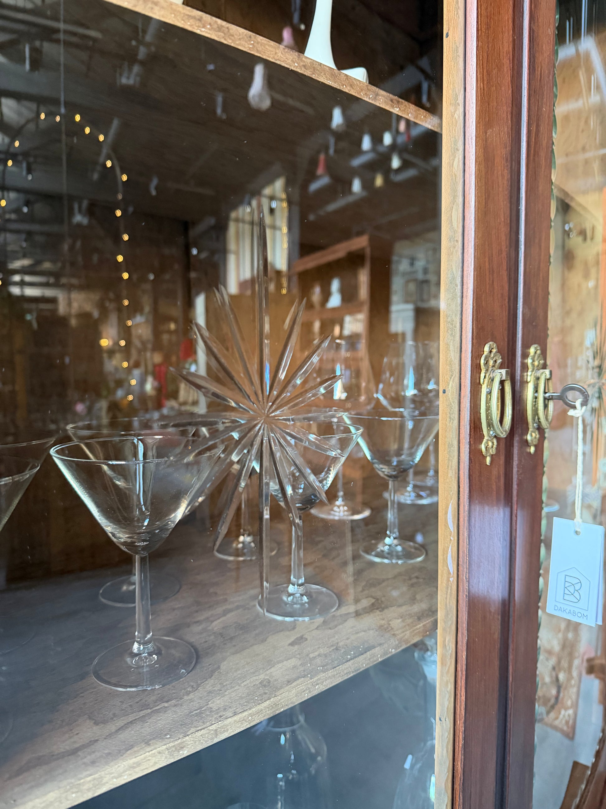 Ett elegant vitrinskåp i vacker Art Nouveau- stil med mjukt svängd front och utsmyckade detaljer som ger en tidlös och exklusiv känsla. Skåpet är tvådelat. Den övre vitrindelen med glasdörrar och hyllplan passar perfekt för att visa upp glas, porslin eller samlarföremål, medan den nedre delen är praktisk för förvaring. Skåpet har originalglas med dekorativ fasettslipning längs glasets kanter och tidstypiska slipade stjärnformade ornament. De mjuka formerna, gedigna hantverket och fantastiska detaljerna i vi