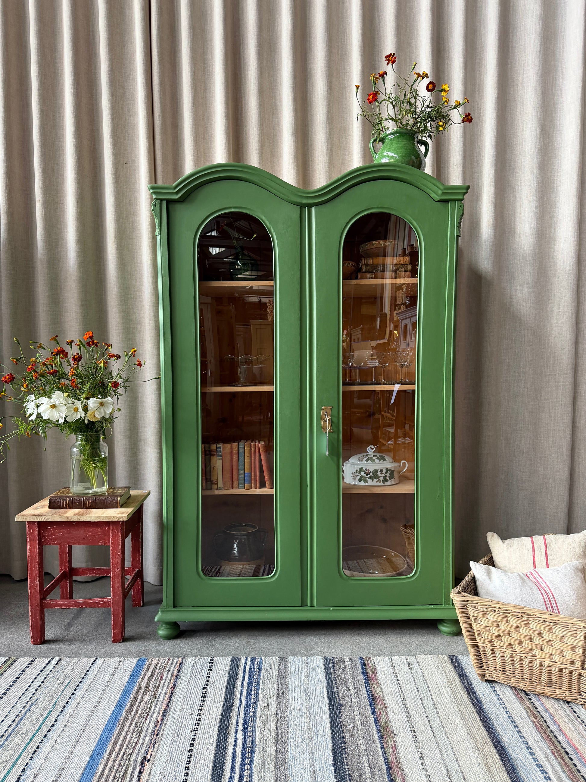 Ett gammalt unikt och charmigt vitrinskåp med vackra runda former i en klargrön färg. Vitrindörrarna lyfter fram ditt porslin, glas eller favoritböcker på ett elegant sätt, medan den gedigna formen, utsmyckningen och de mjuka detaljerna ger skåpet karaktär. Ett riktigt blickfång som lyfter rummet och passar såväl in i köket som vardagsrummet. Skåpet är varsamt renoverat och sedan penselmålat med en matt snickerifärg i Dakaboms klargröna kulör.