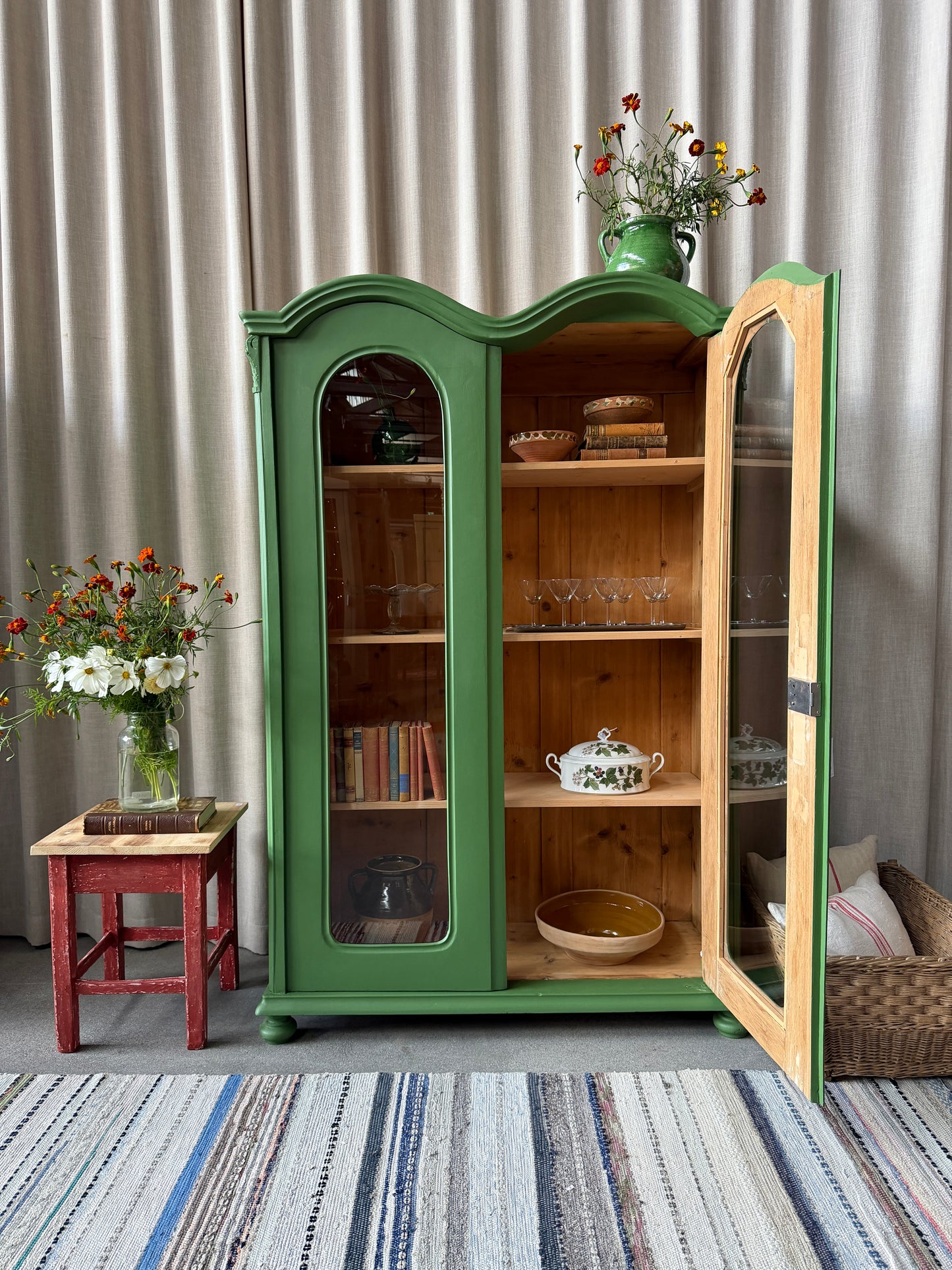 Ett gammalt unikt och charmigt vitrinskåp med vackra runda former i en klargrön färg. Vitrindörrarna lyfter fram ditt porslin, glas eller favoritböcker på ett elegant sätt, medan den gedigna formen, utsmyckningen och de mjuka detaljerna ger skåpet karaktär. Ett riktigt blickfång som lyfter rummet och passar såväl in i köket som vardagsrummet. Skåpet är varsamt renoverat och sedan penselmålat med en matt snickerifärg i Dakaboms klargröna kulör.