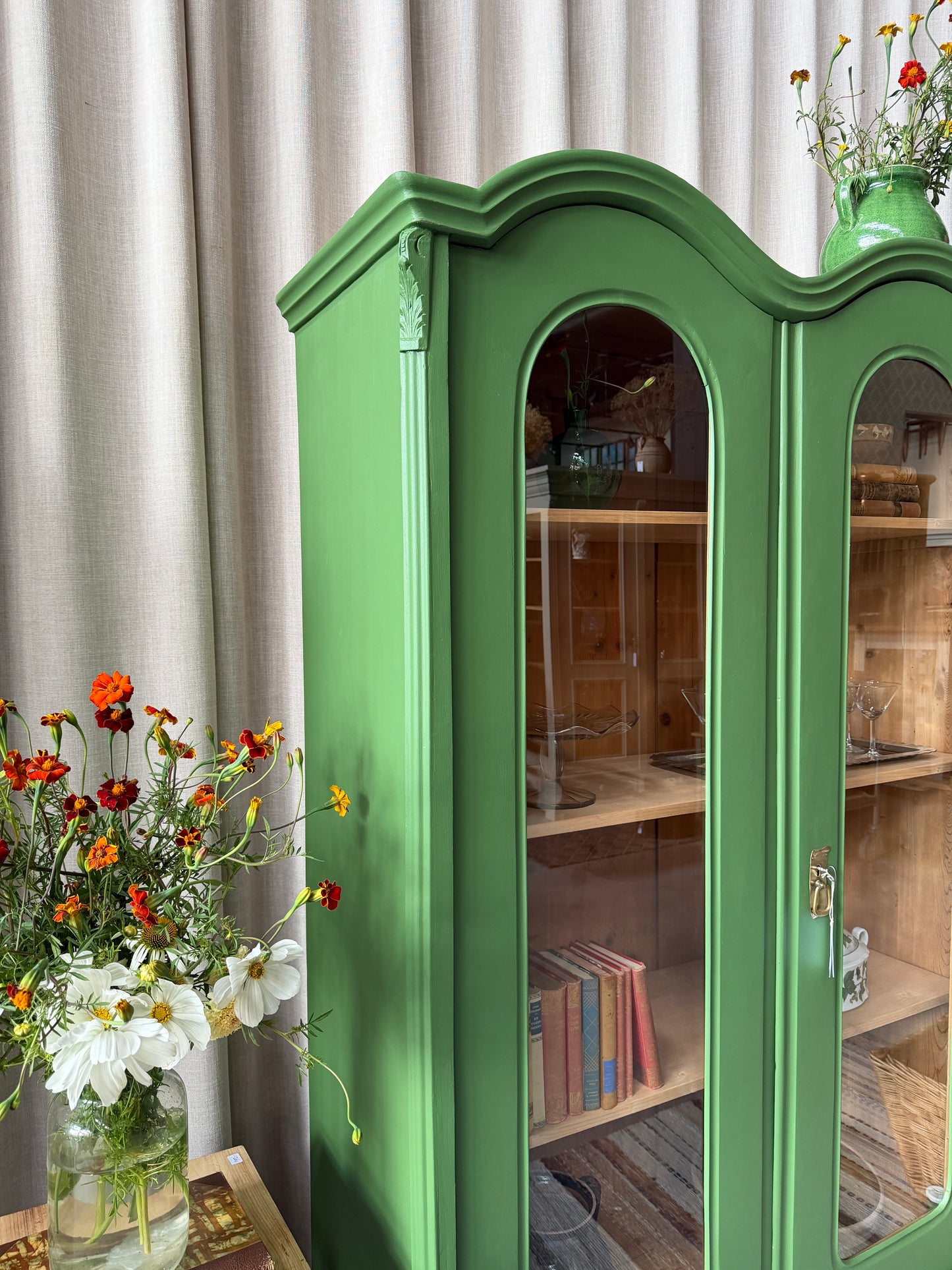 Ett gammalt unikt och charmigt vitrinskåp med vackra runda former i en klargrön färg. Vitrindörrarna lyfter fram ditt porslin, glas eller favoritböcker på ett elegant sätt, medan den gedigna formen, utsmyckningen och de mjuka detaljerna ger skåpet karaktär. Ett riktigt blickfång som lyfter rummet och passar såväl in i köket som vardagsrummet. Skåpet är varsamt renoverat och sedan penselmålat med en matt snickerifärg i Dakaboms klargröna kulör.